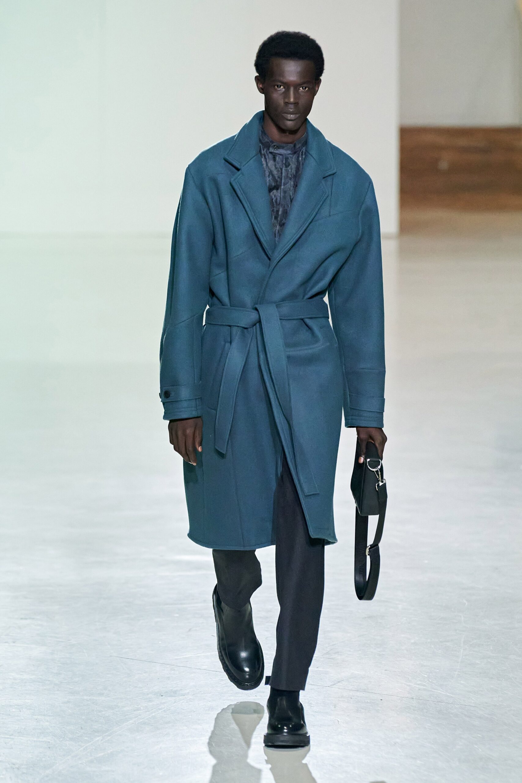 A relaxed blue wool coat with long sleeves and a belted design.