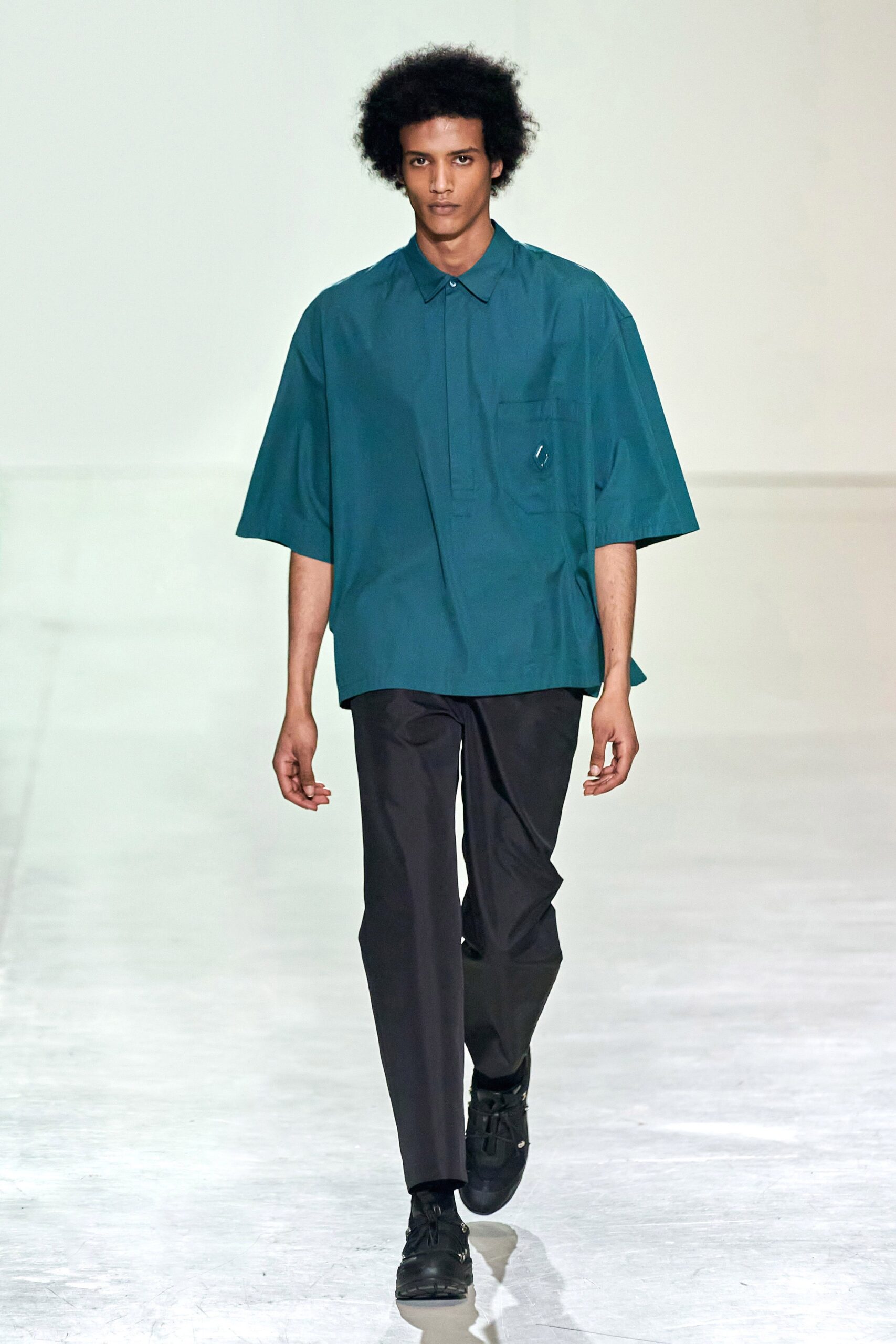 A relaxed blue short-sleeve collared shirt paired with straight-leg black pants.