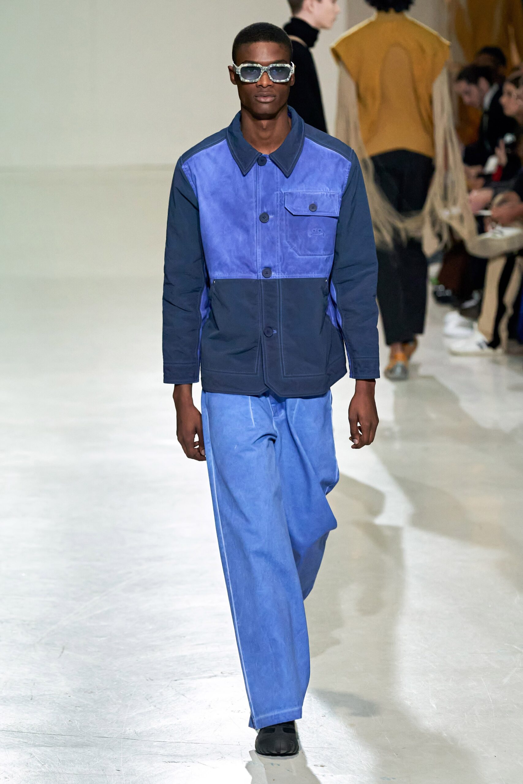 A relaxed blue denim jacket with long sleeves and a collared neckline paired with wide-leg pants.