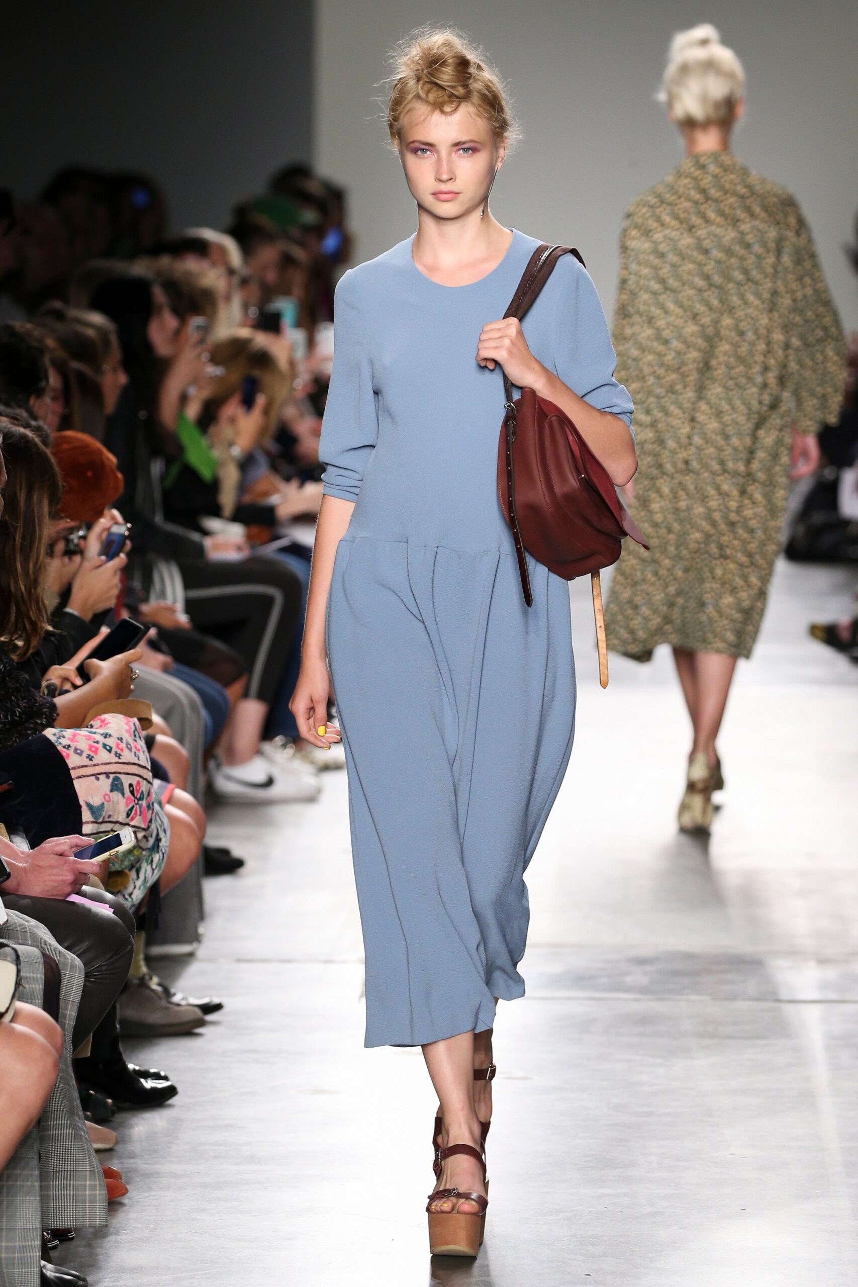 A relaxed blue cotton dress with long sleeves and a V-neckline featuring a tiered design.
