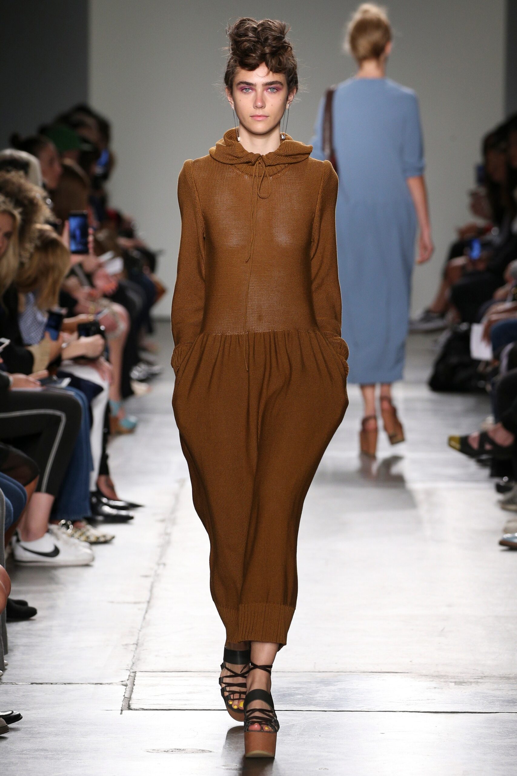 A relaxed brown cotton jumpsuit with a hood and pleated details.