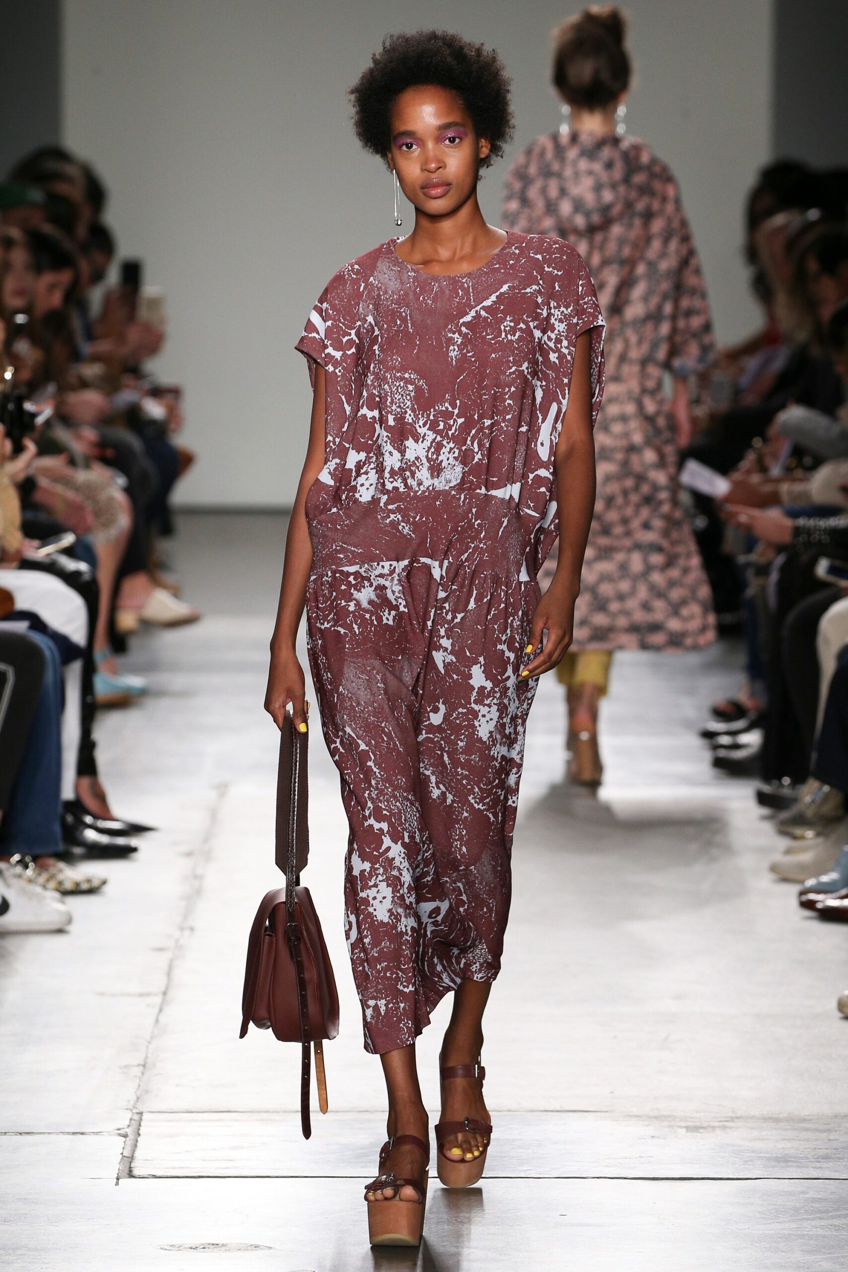 A relaxed brown printed jumpsuit with short sleeves and a collared neckline.