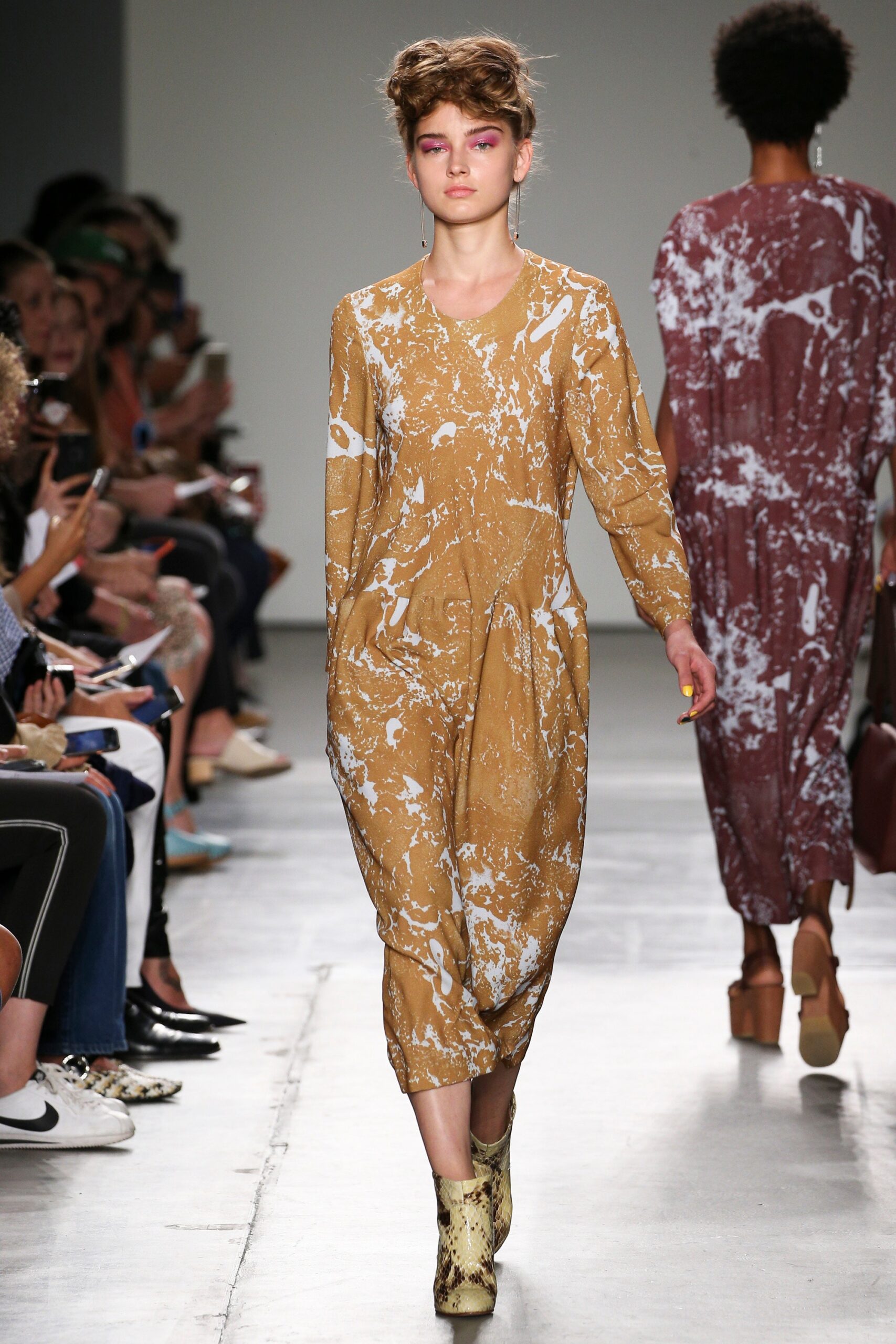 A relaxed brown cotton dress with long sleeves and a V-neckline featuring a unique print.