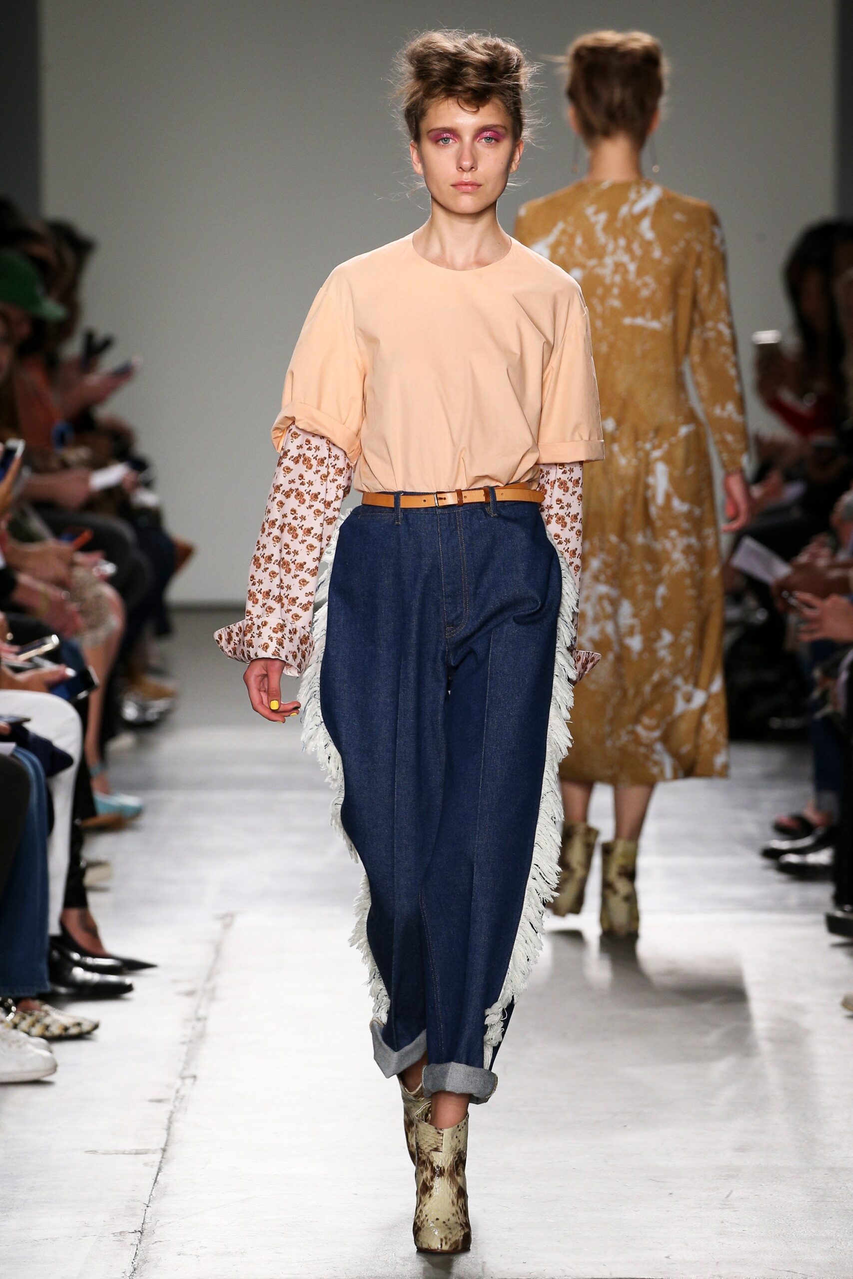 A relaxed beige top with short sleeves paired with flared blue denim pants.