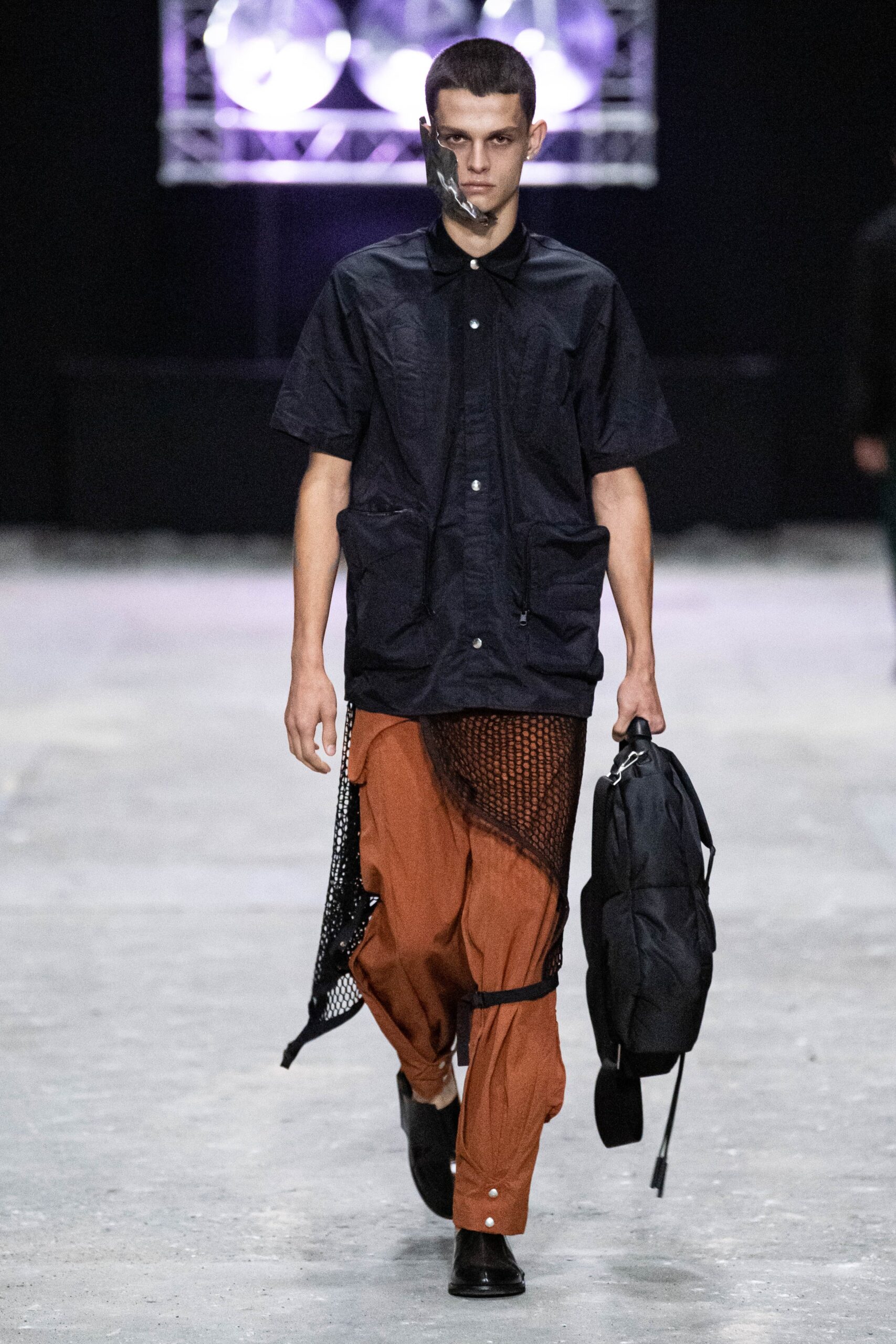 A relaxed black short-sleeve collared shirt paired with layered brown pants.