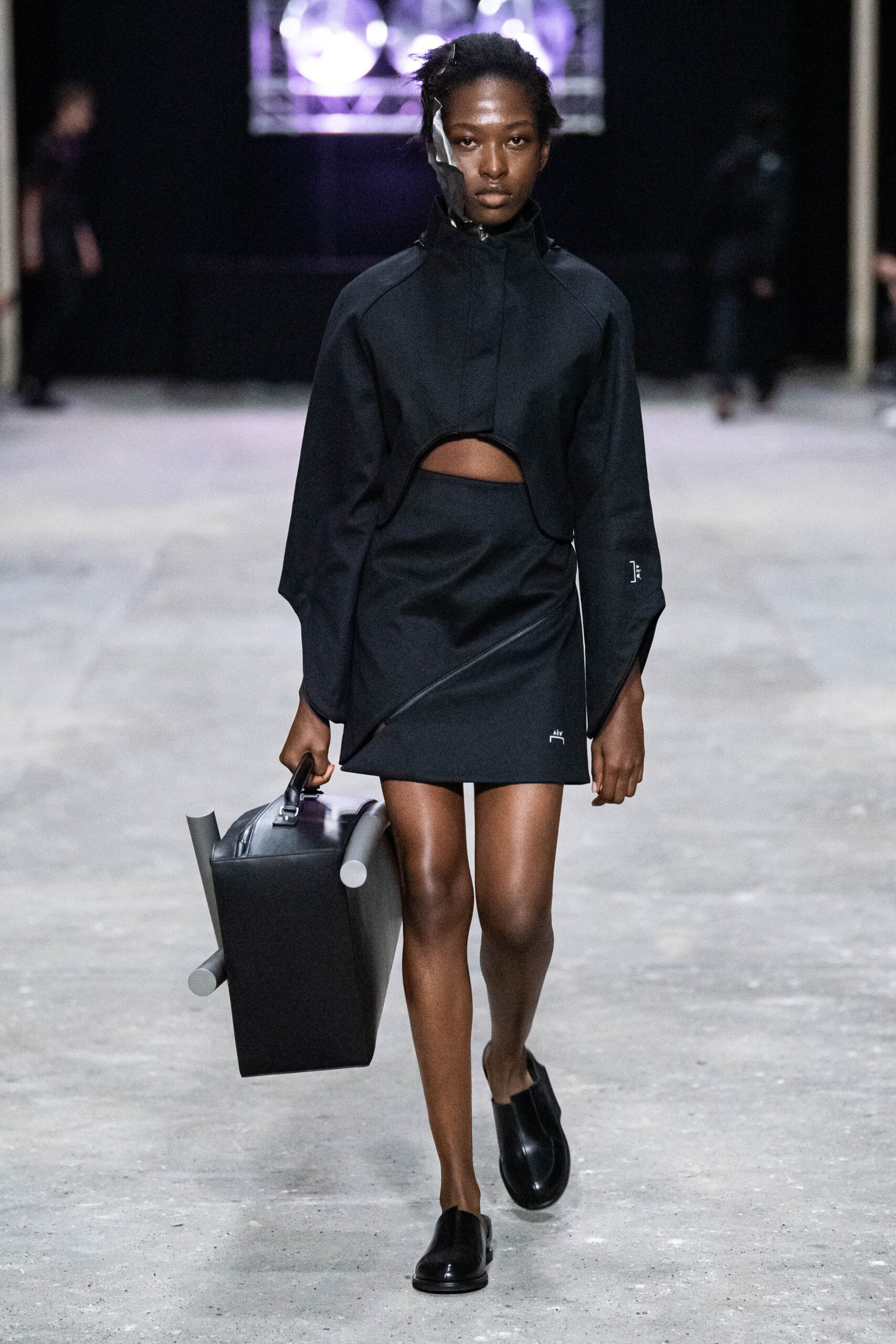 A fitted black dress with a high-neck jacket featuring a cutout and asymmetric design.