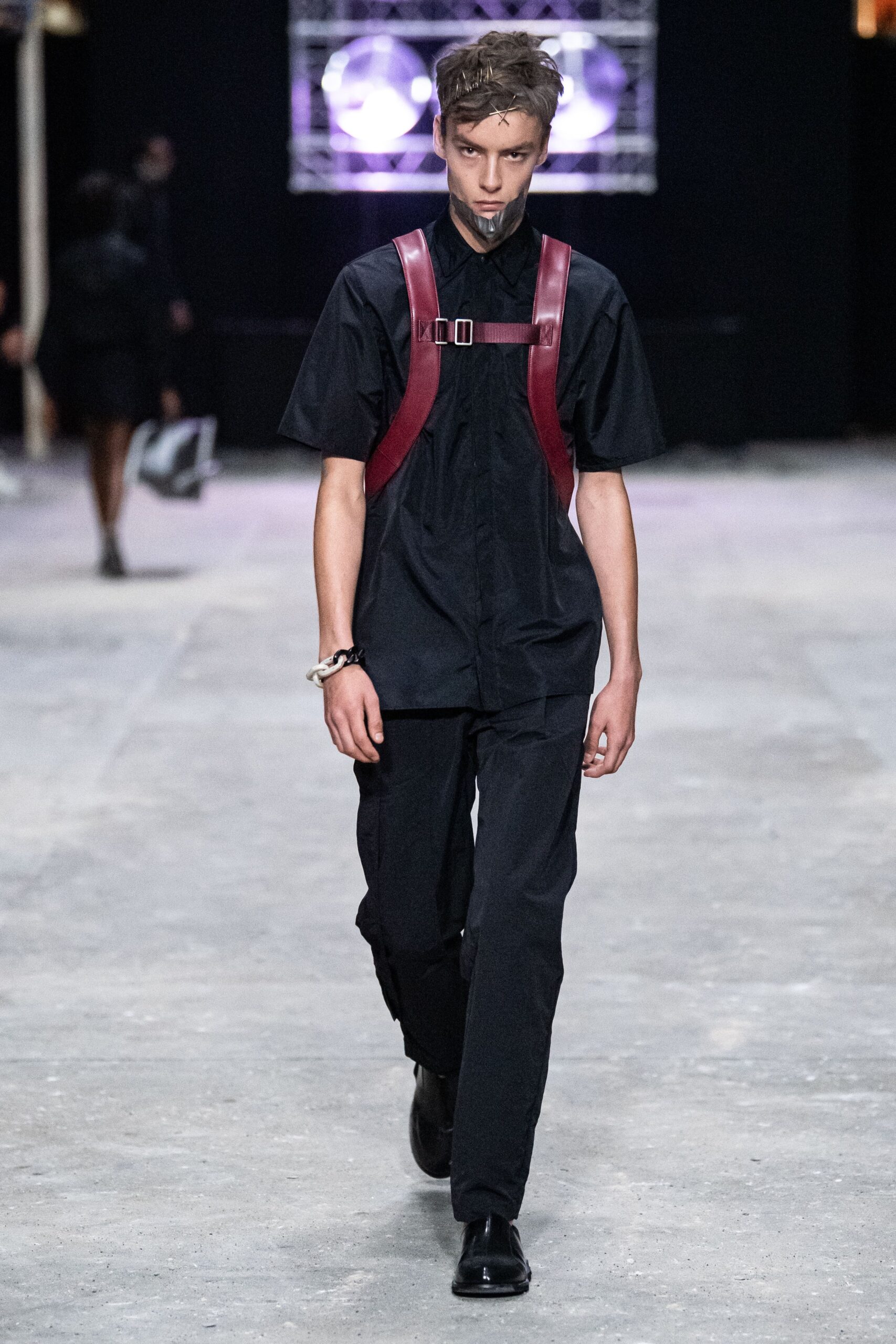A fitted black short-sleeve shirt with a collared neckline paired with straight-leg pants.