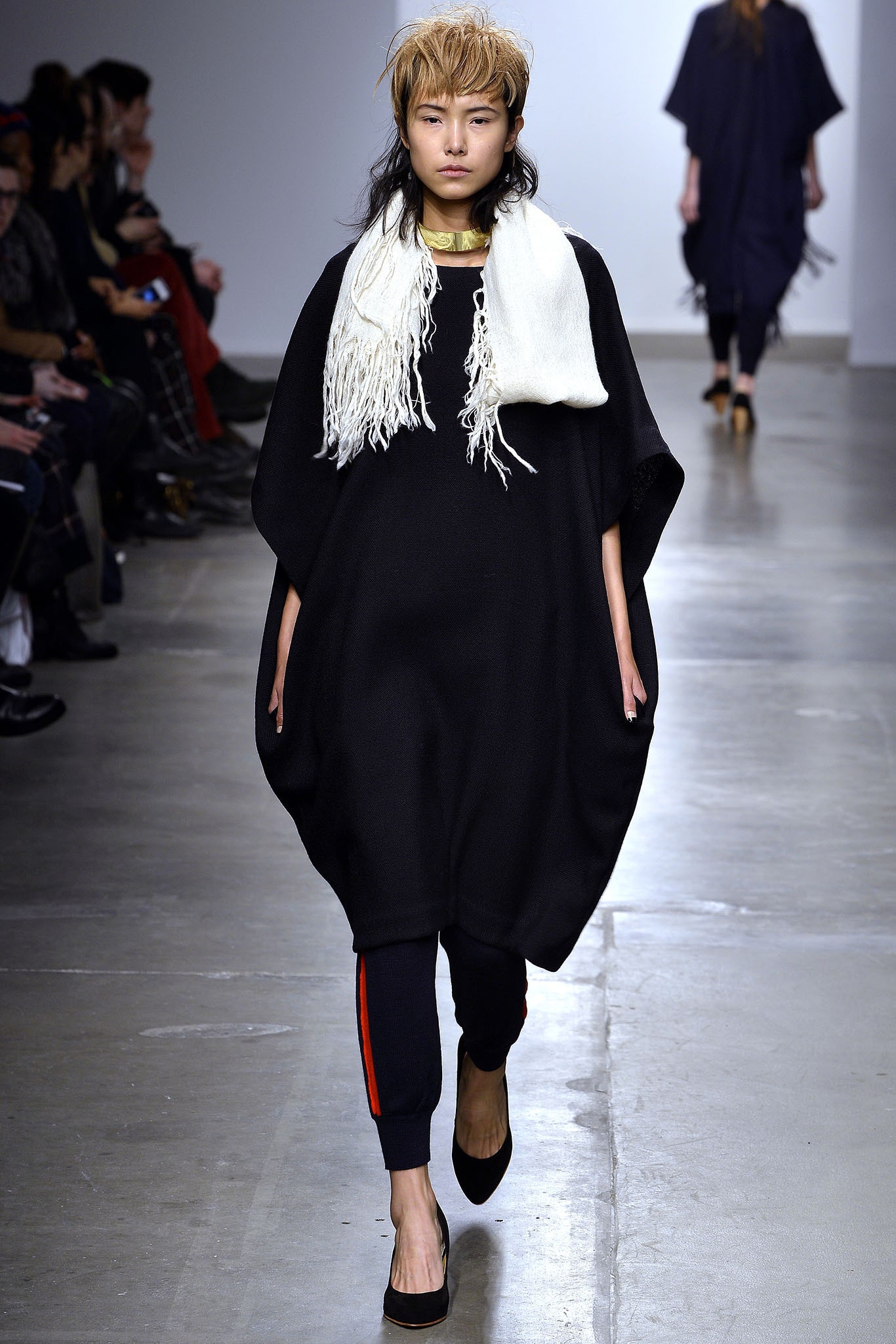 An oversized black cotton poncho paired with black pants, featuring a layered design.