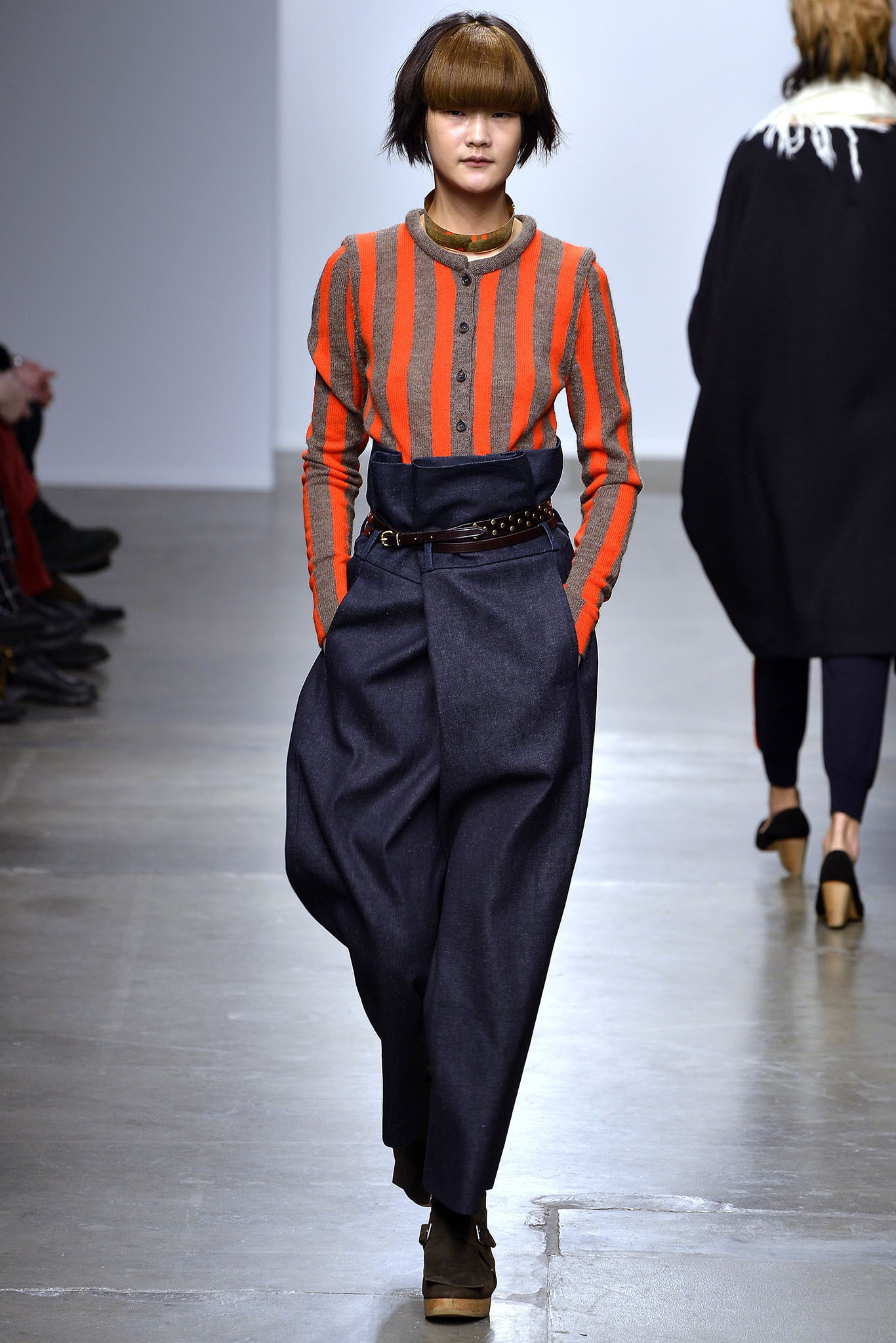 A relaxed outfit featuring a long-sleeve striped orange top and wide-leg blue pants.
