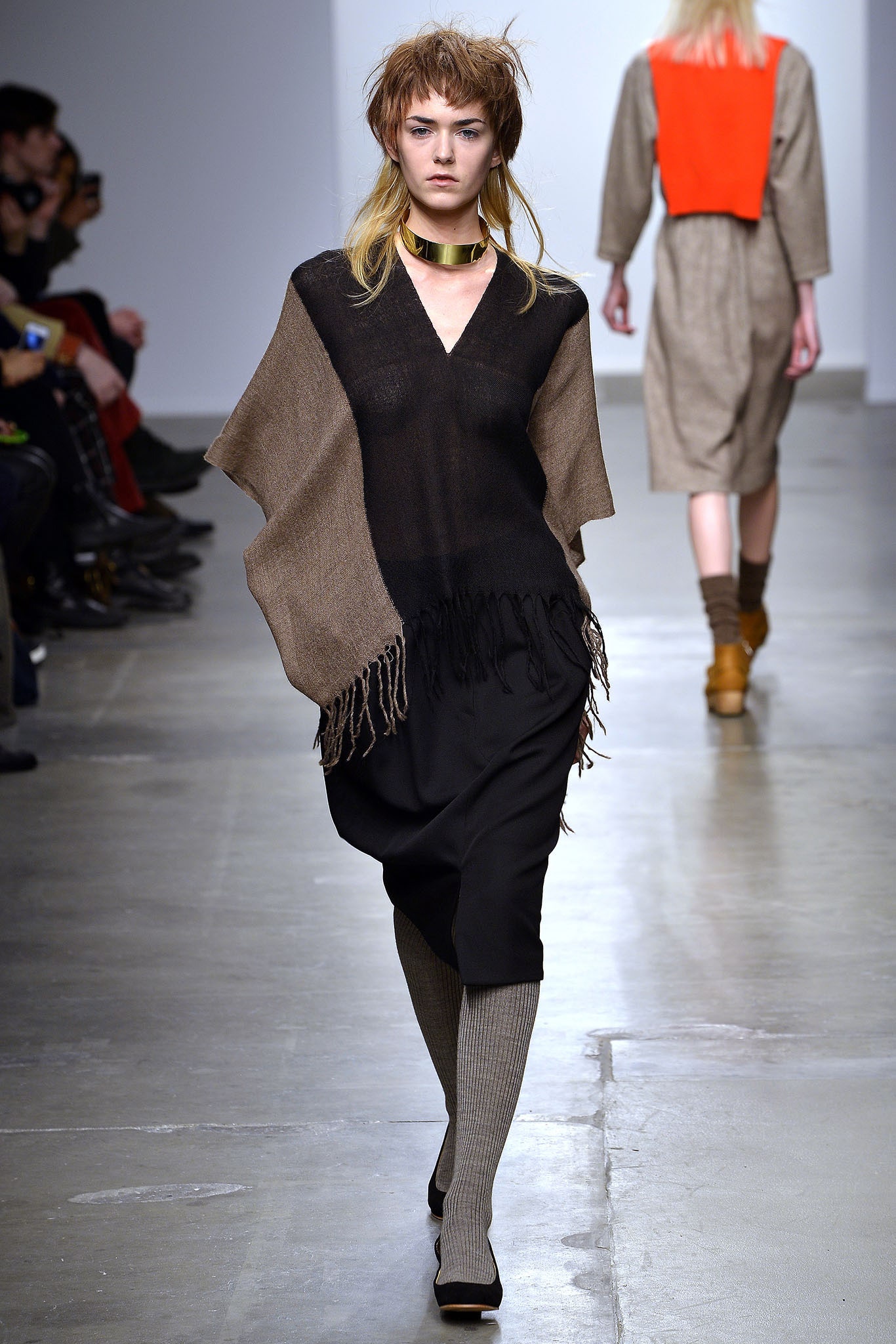 A relaxed black and brown poncho dress with a V-neckline and asymmetric design featuring fringed details.