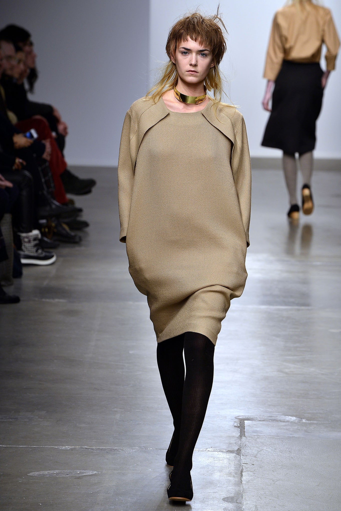 An oversized beige cotton dress with long sleeves and an asymmetric design.