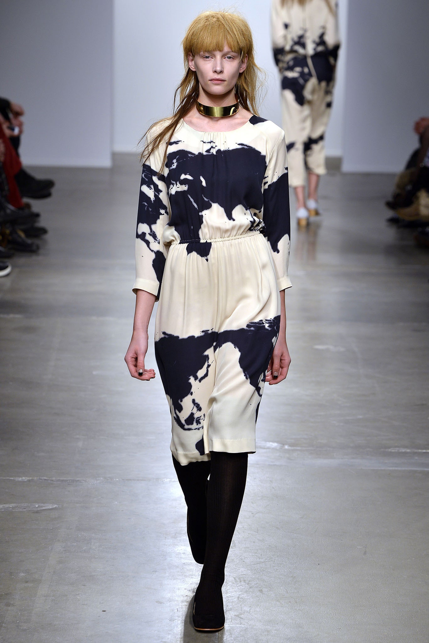 A fitted cream and black printed dress with long sleeves and a collared neckline.