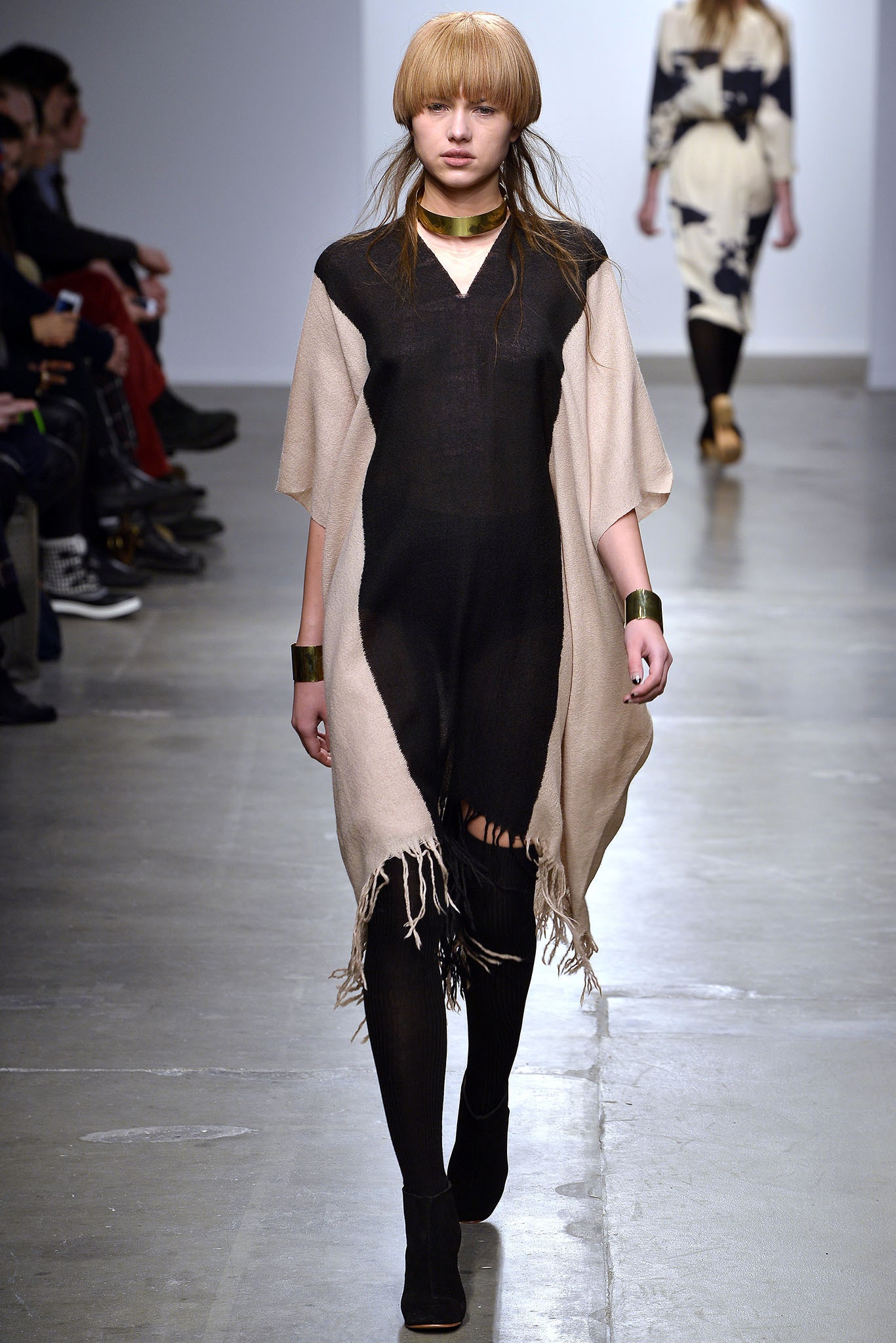 A relaxed black and beige sleeveless dress with a V-neckline and asymmetric fringed detail.