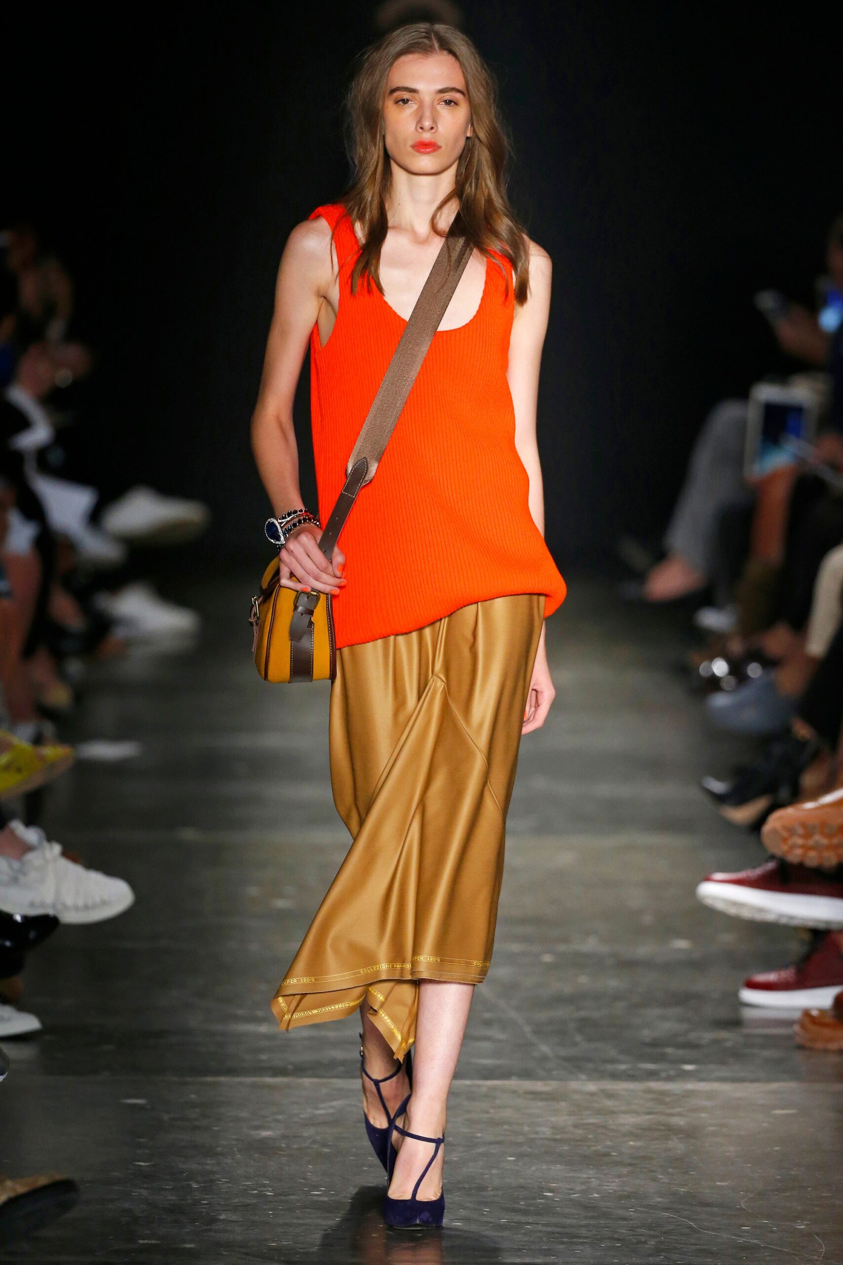 A relaxed orange sleeveless top paired with an asymmetric gold skirt.