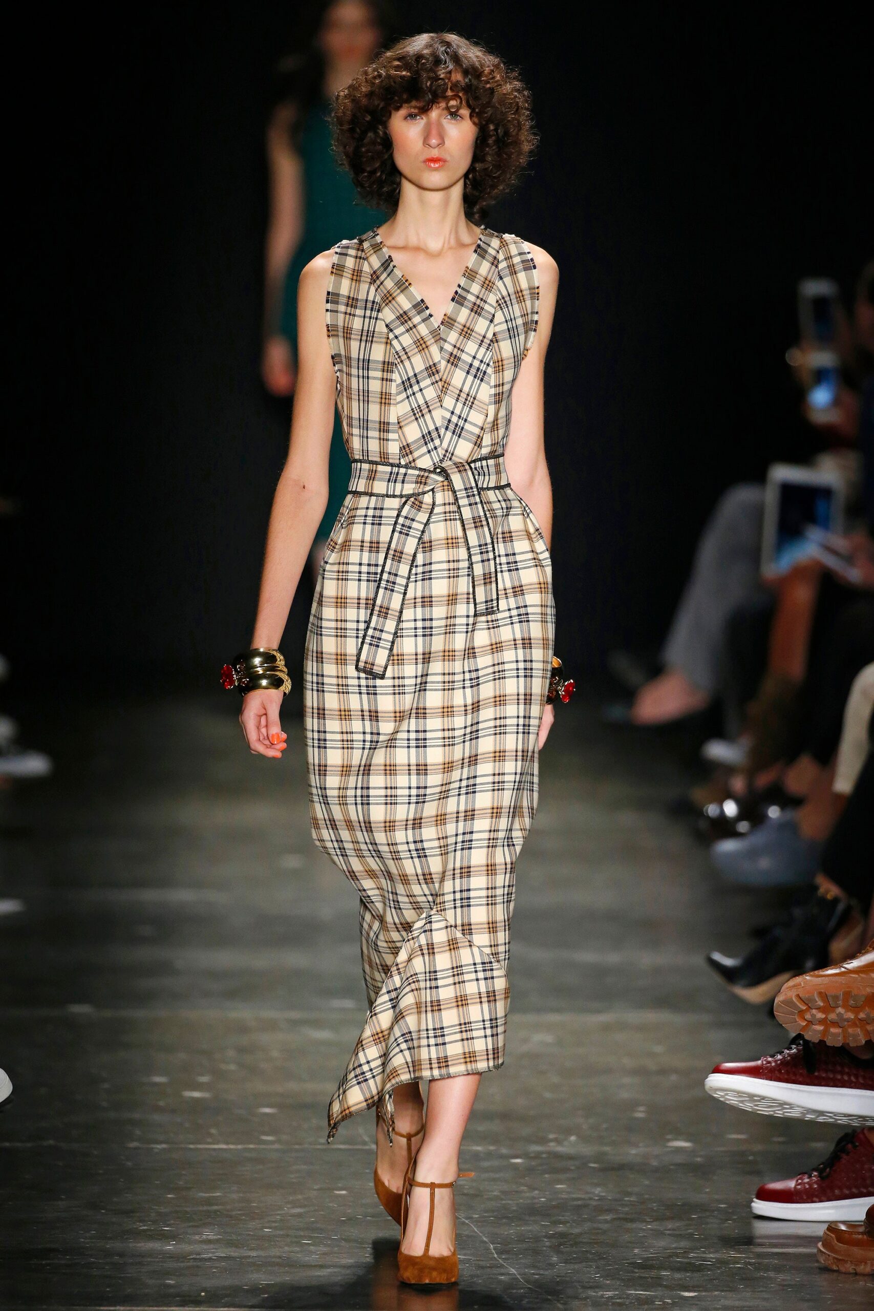 A fitted beige checked sleeveless dress with a V-neckline and a belted waist.