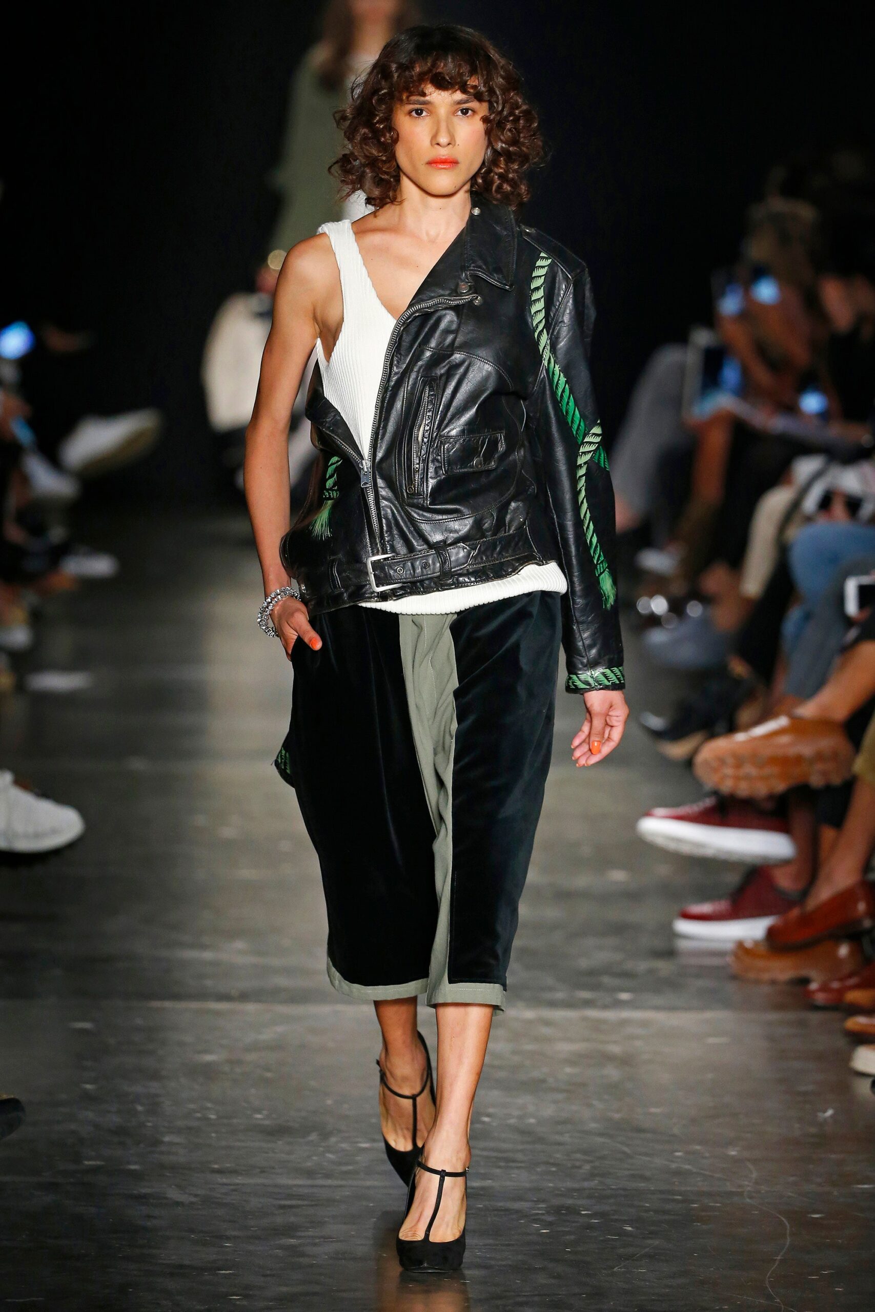 A fitted black leather asymmetric jacket paired with wide-leg green velvet pants.