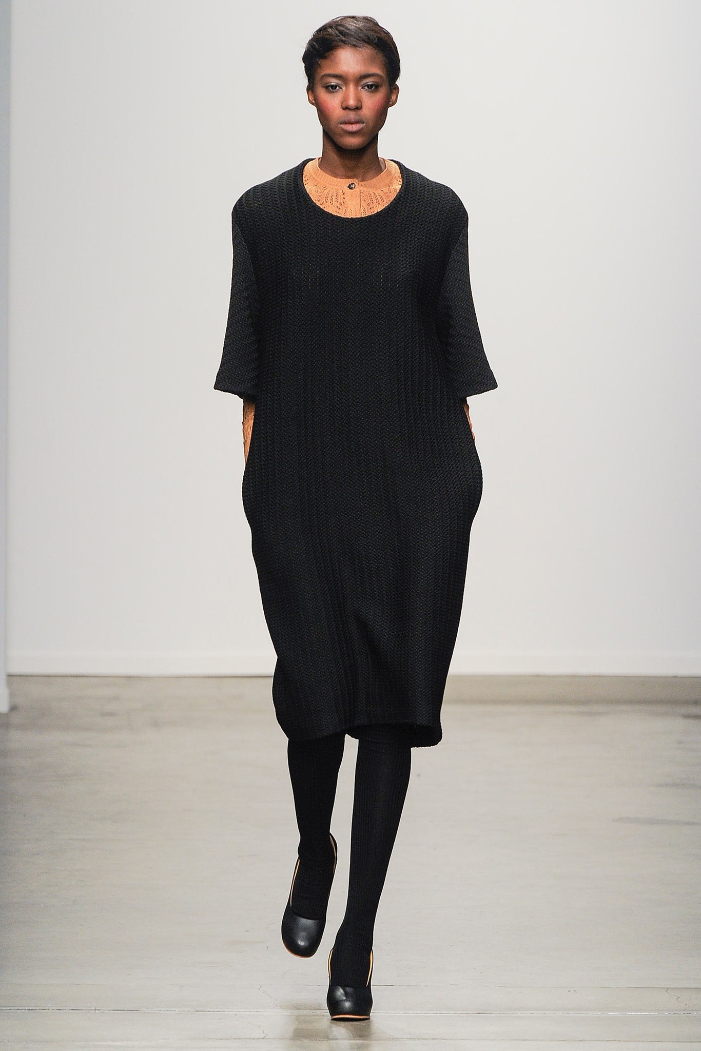 A relaxed black knit dress with short sleeves and a crew neckline.