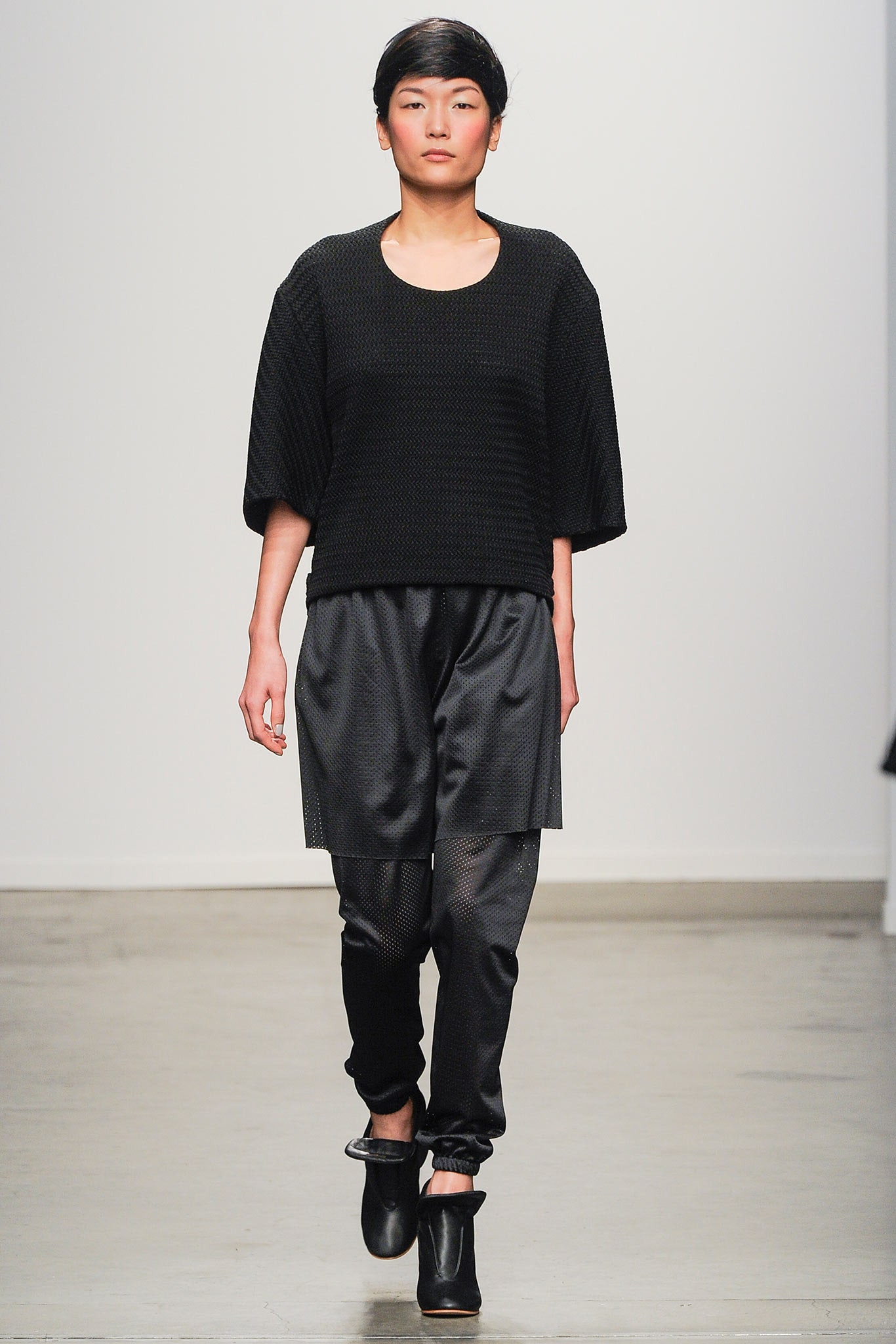 A relaxed black top with short sleeves paired with black pants, featuring a layered design.