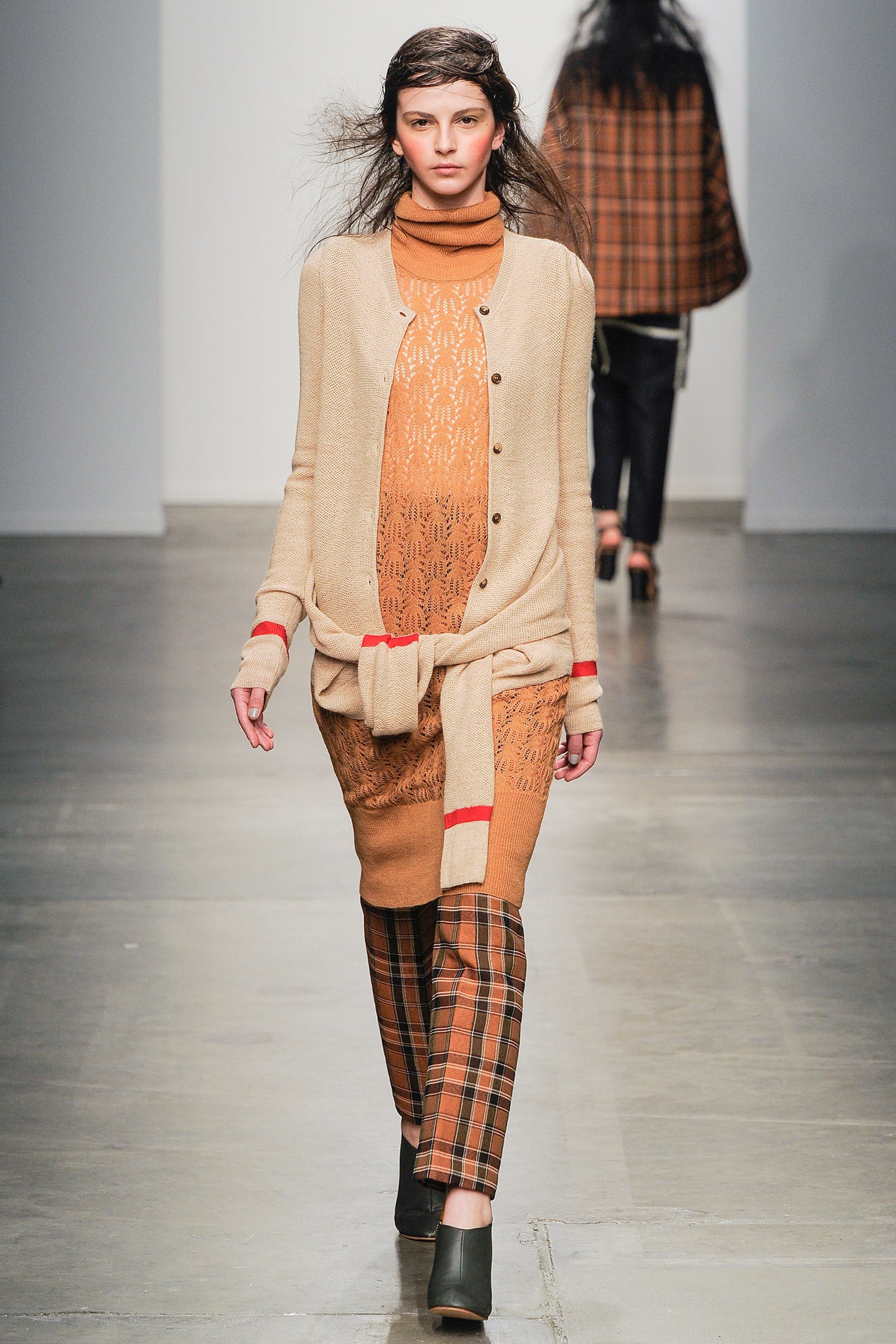 A fitted beige cotton dress with long sleeves, layered design, and checked pants.