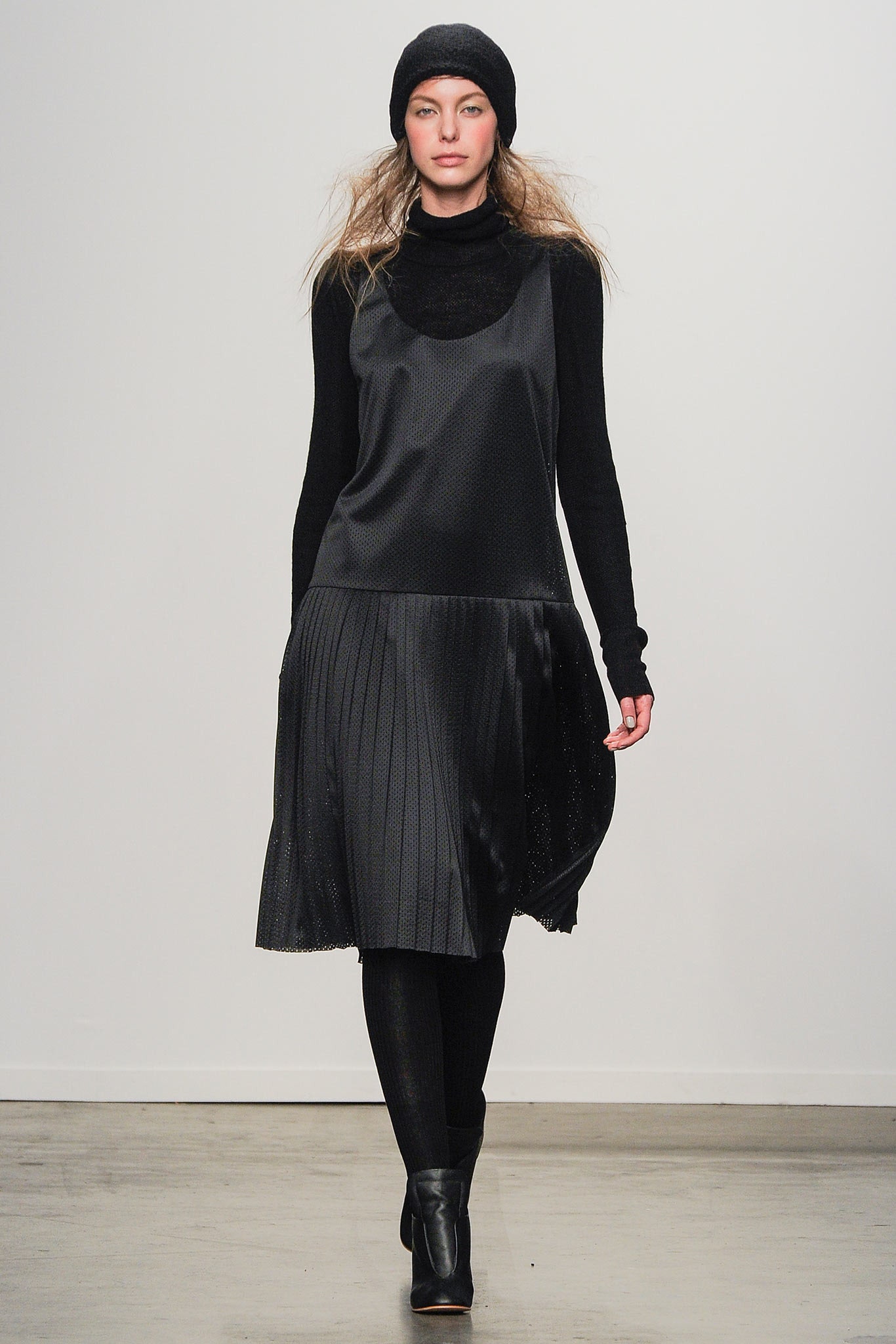 A relaxed black silk sleeveless dress with a high neckline and pleated design.