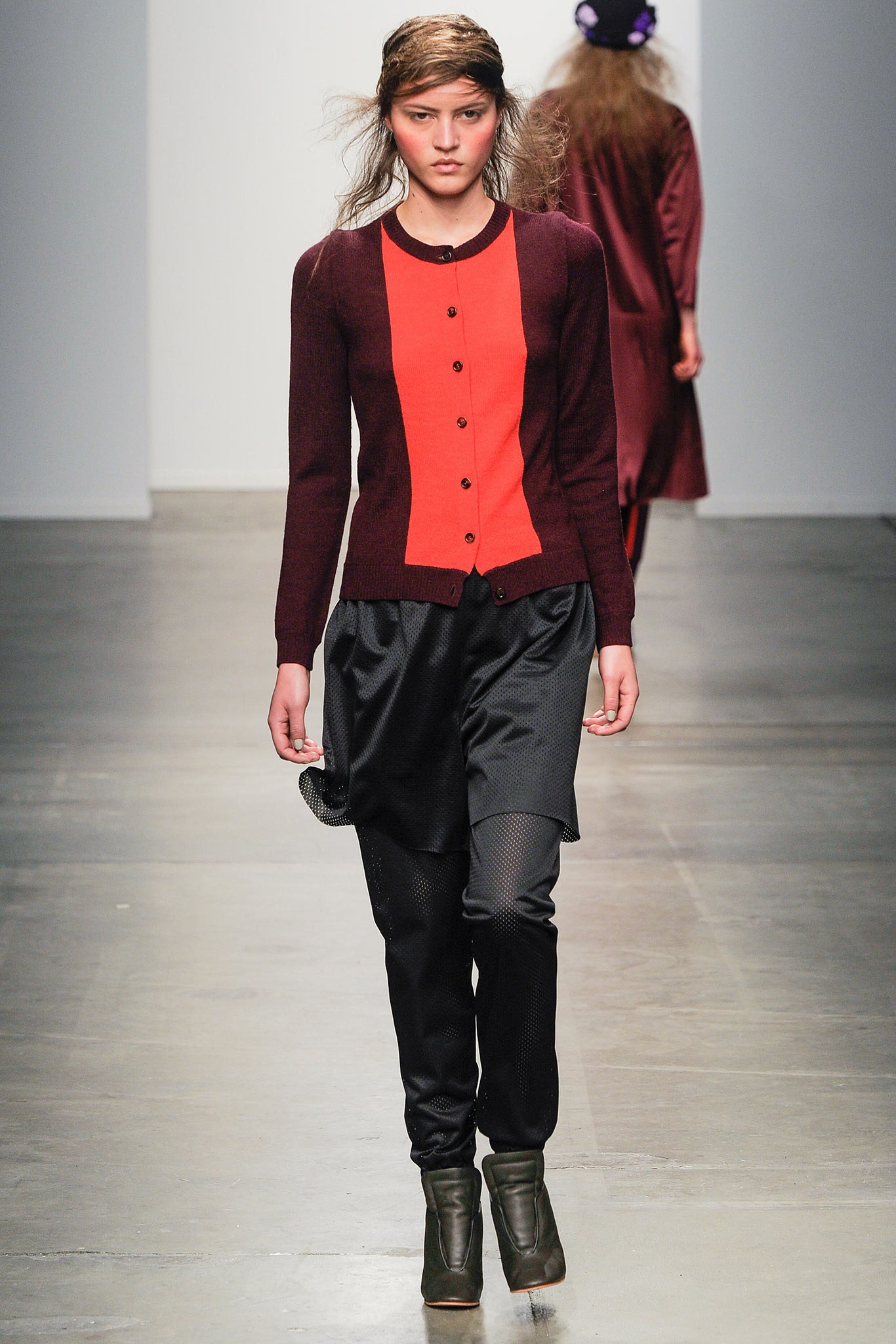 A fitted red and brown long-sleeve cardigan paired with black pants, featuring a buttoned design.