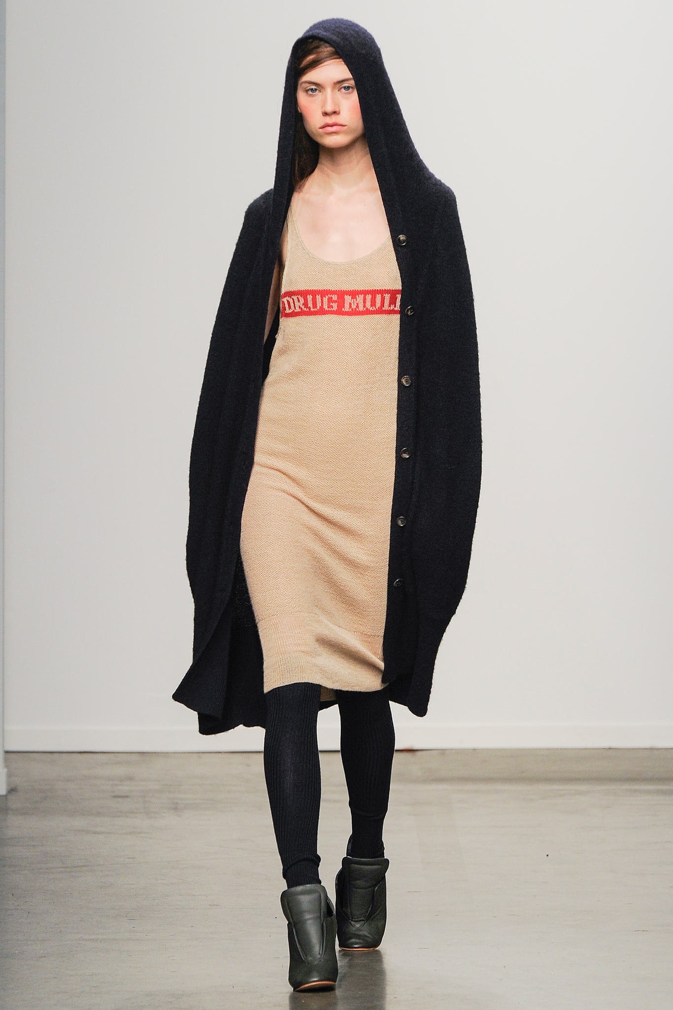 A fitted beige sleeveless dress layered under a long-sleeve black coat with button details.