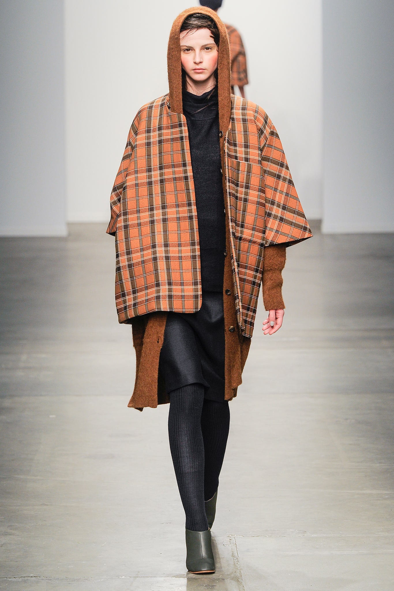 A relaxed brown and orange checked coat layered over a black dress.