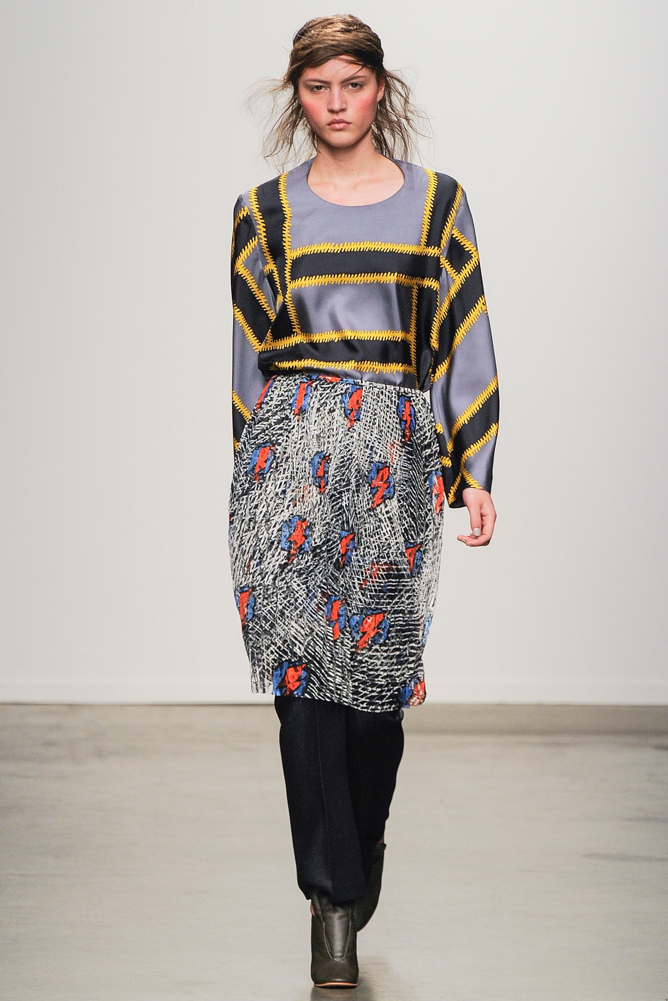 A relaxed gray long-sleeve top paired with a multicolor printed skirt.
