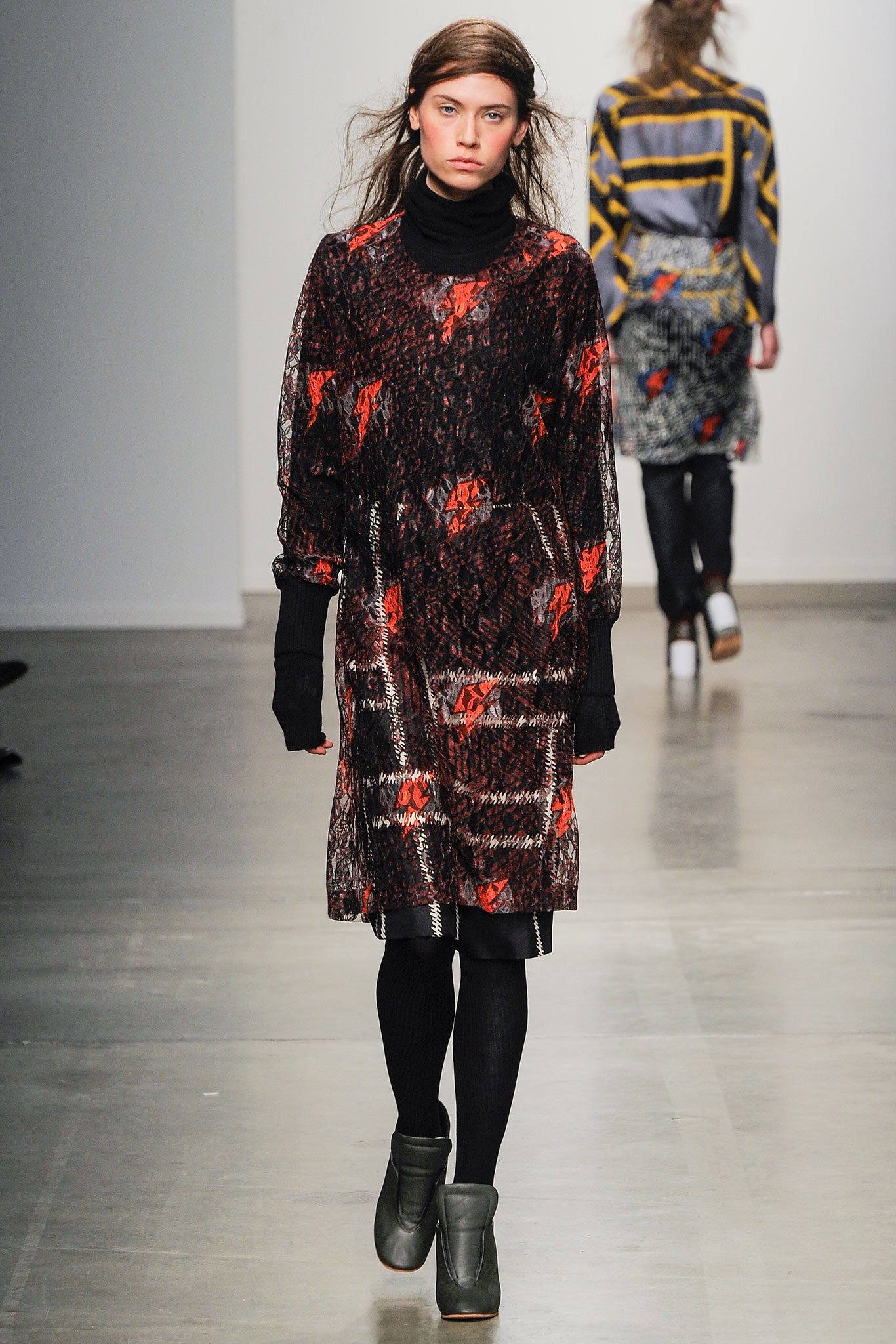 A relaxed black dress with floral patterns, long sleeves, and a high neckline.