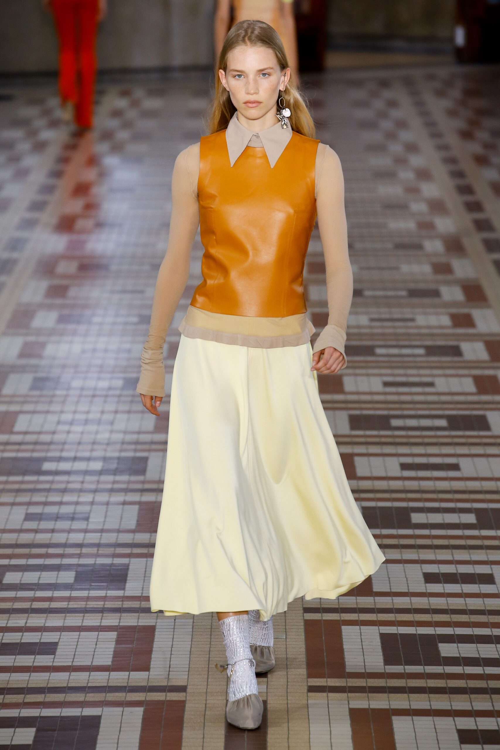 orange leather sleeveless top and white pleated skirt