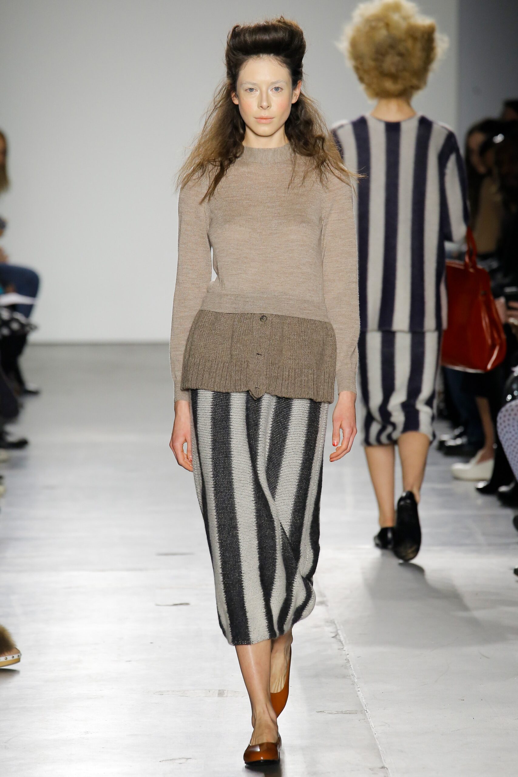 A fitted beige wool long-sleeve top paired with a striped skirt featuring an asymmetric design.