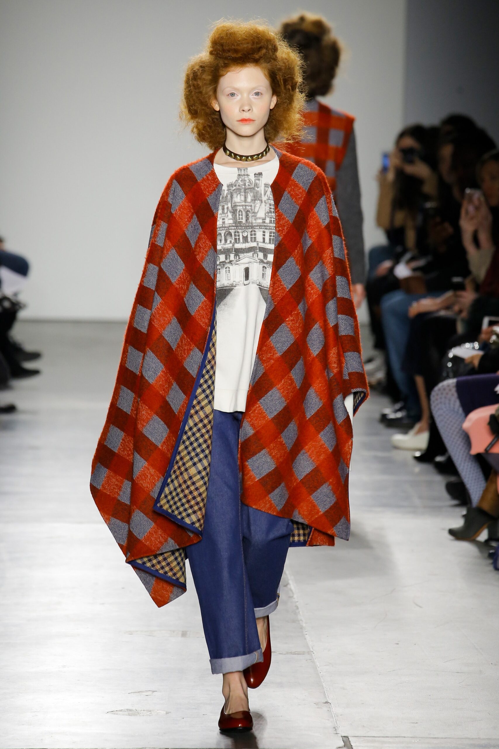 A relaxed red checked poncho paired with blue pants, featuring a collared long-sleeve design.
