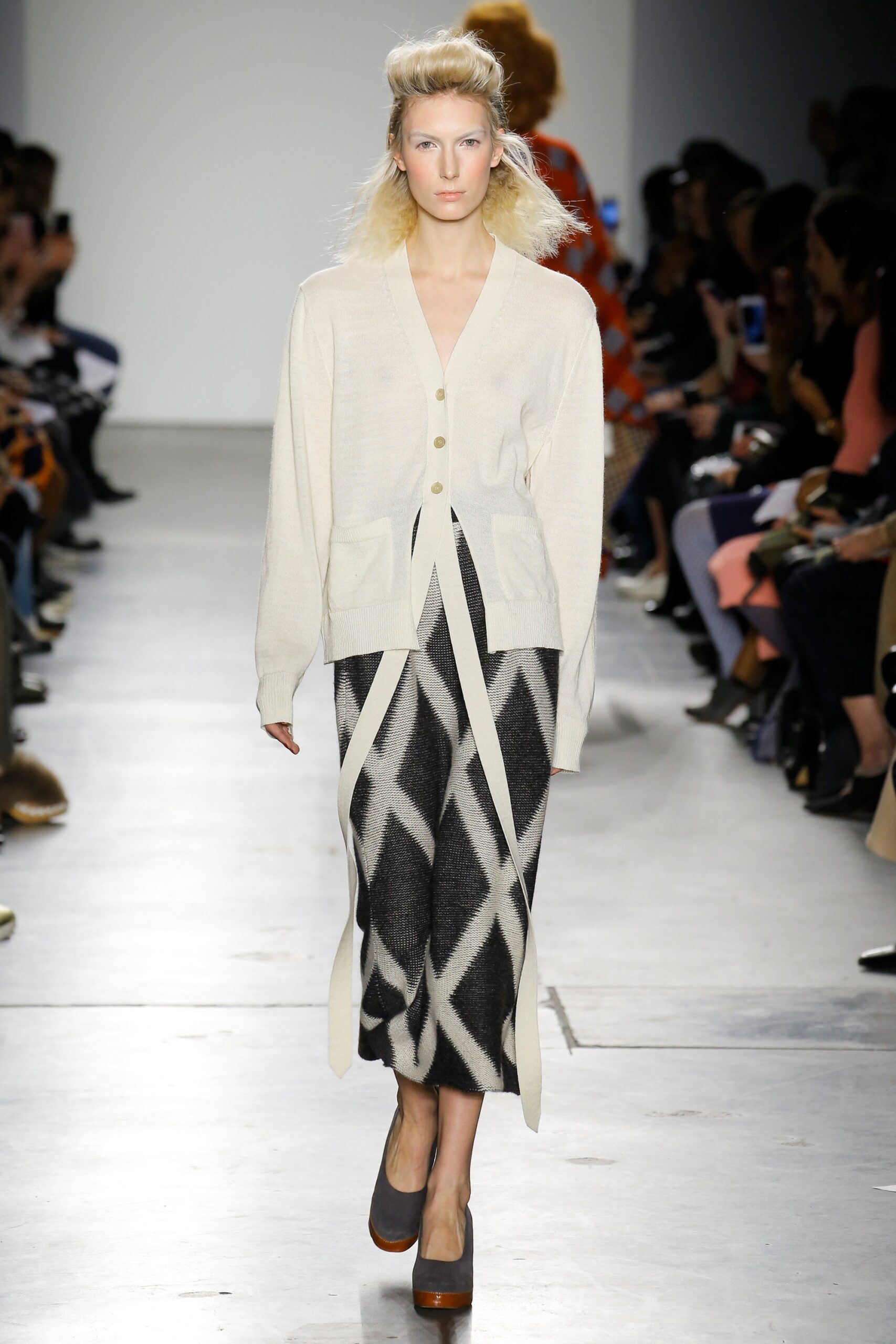 A relaxed beige wool cardigan paired with a tiered black skirt featuring an asymmetric design.
