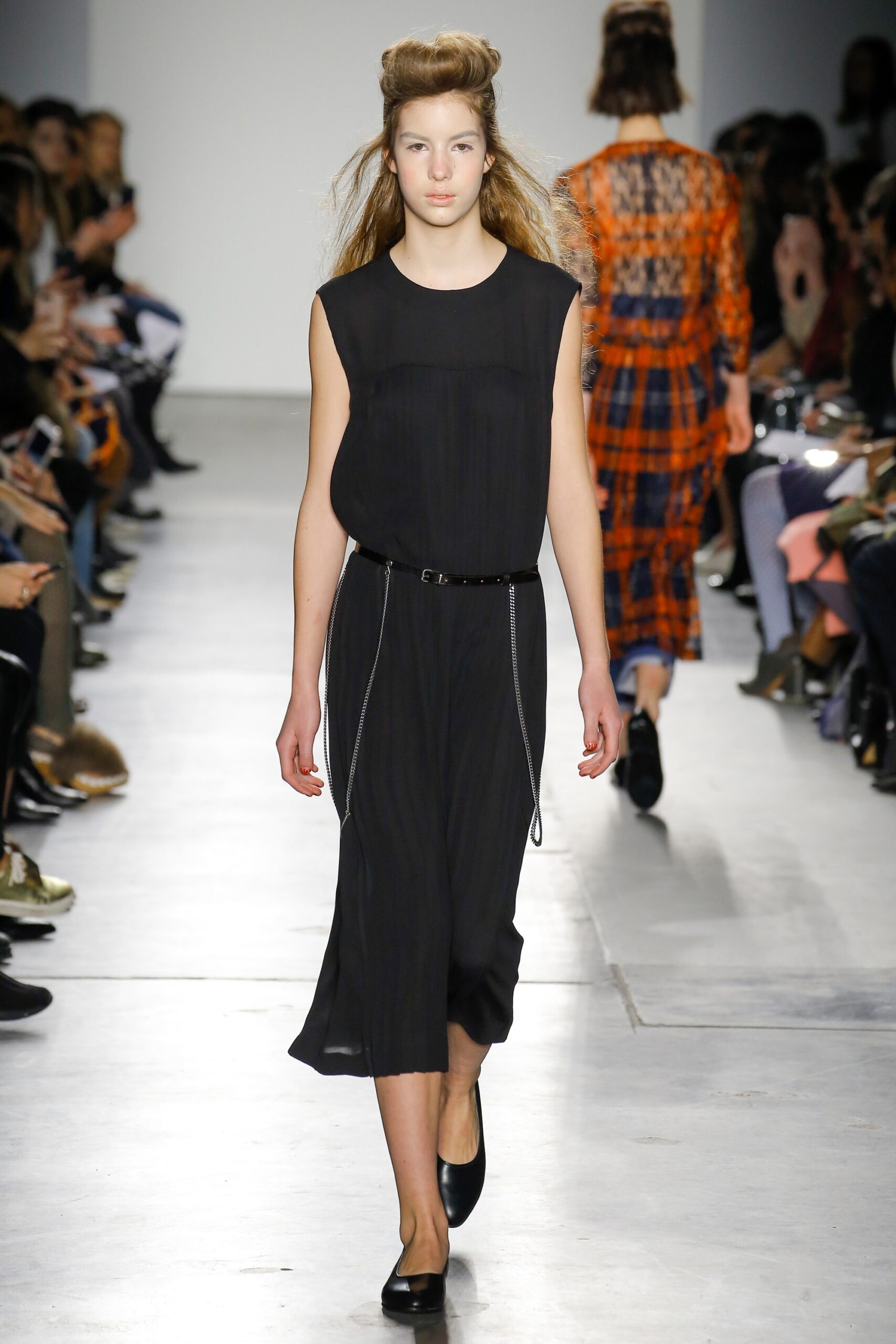 A relaxed black cotton dress with a sleeveless design and high-neck construction.