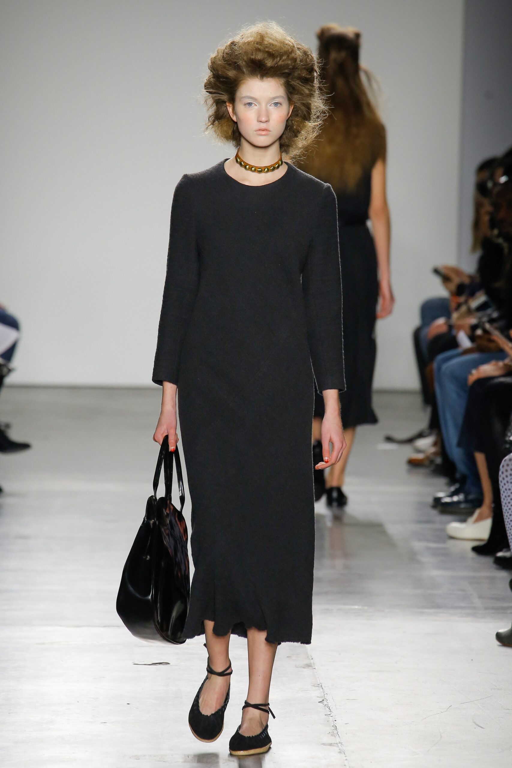 A fitted black cotton dress with long sleeves and a crew neckline.