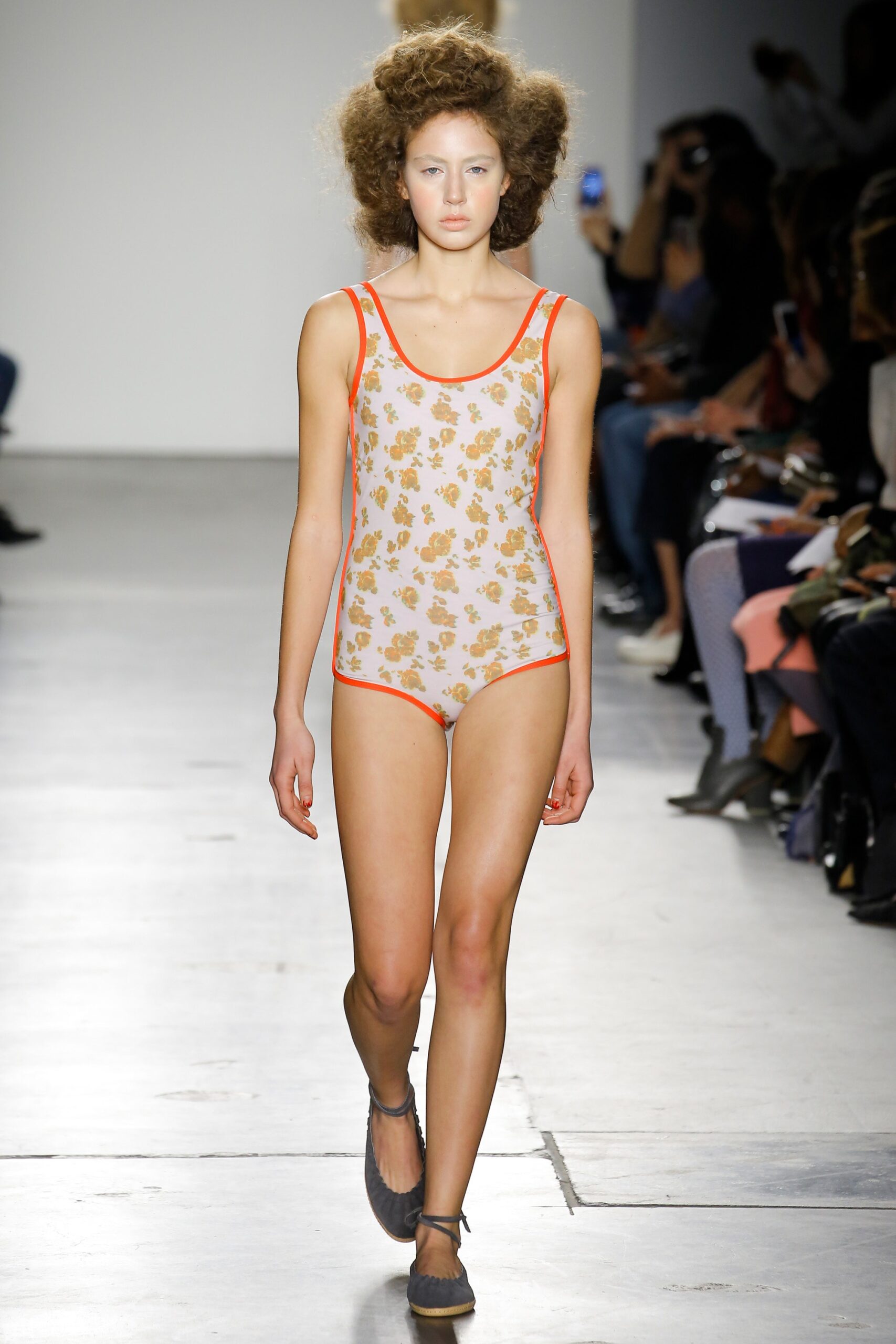 A fitted beige swimsuit with orange trim and a low-cut design featuring a floral print.