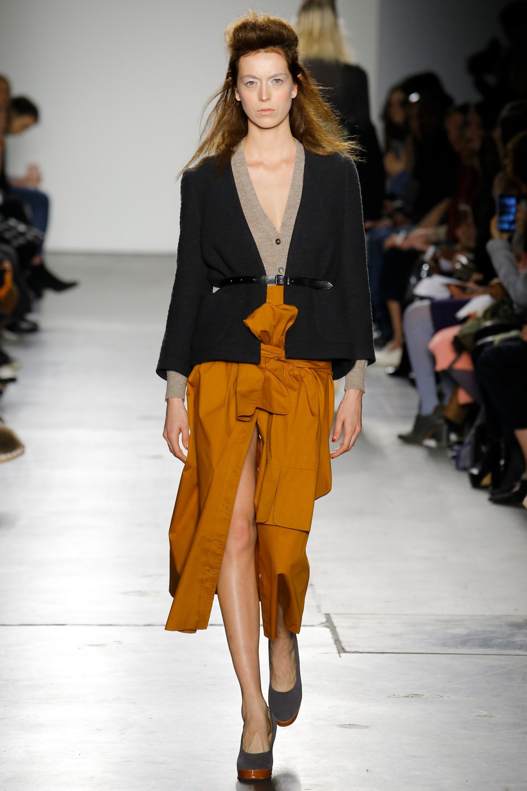 A fitted orange sleeveless dress with a V-neckline and asymmetric design detail.