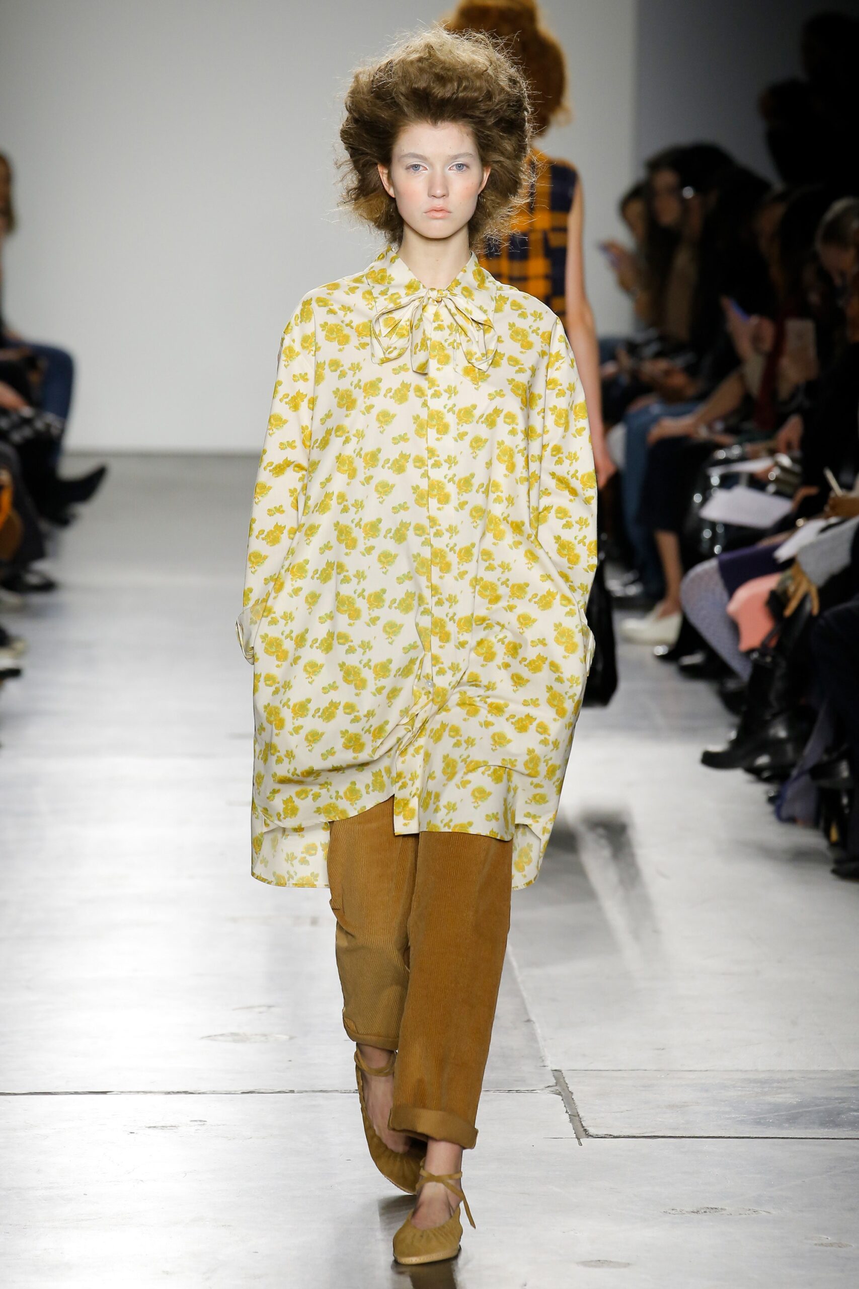 A relaxed yellow floral long-sleeve shirt paired with brown pants for a casual look.