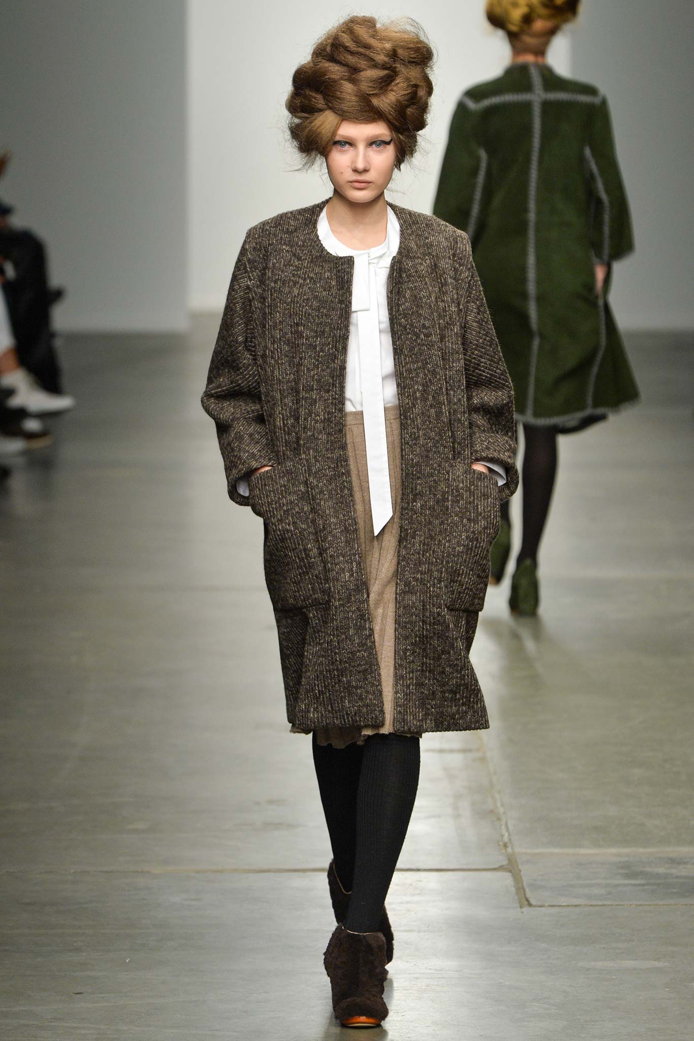 A relaxed brown wool coat with long sleeves and a collared design, featuring button details.