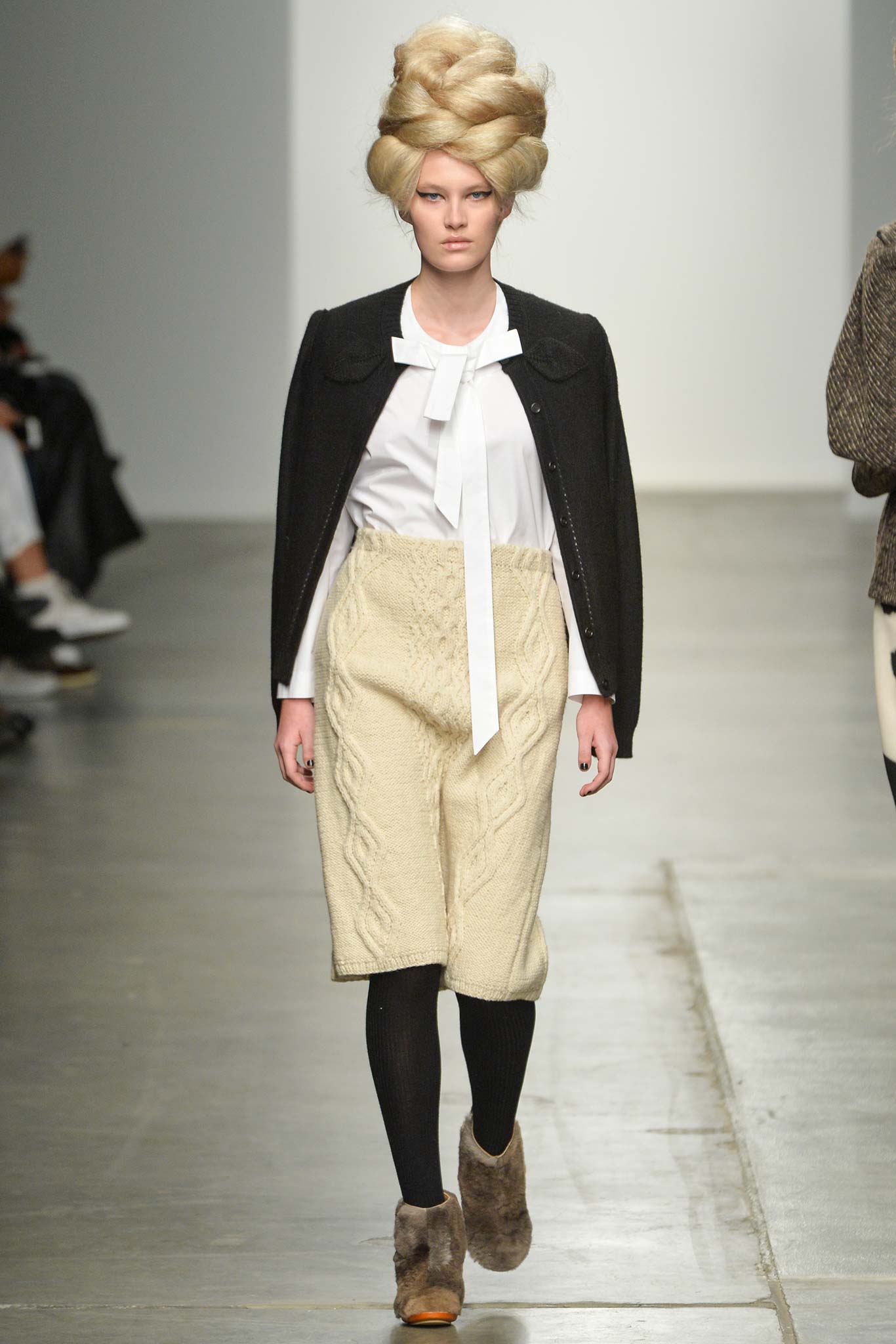 A fitted white long-sleeve blouse with a collared neckline paired with a pleated beige skirt.