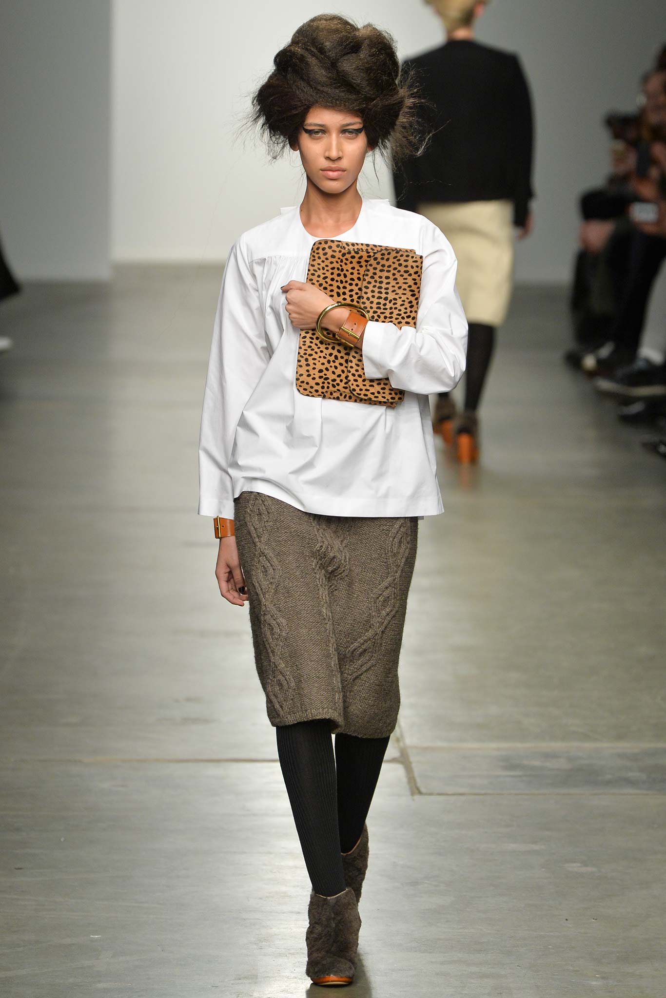 A fitted white long-sleeve collared top paired with a pleated brown skirt.