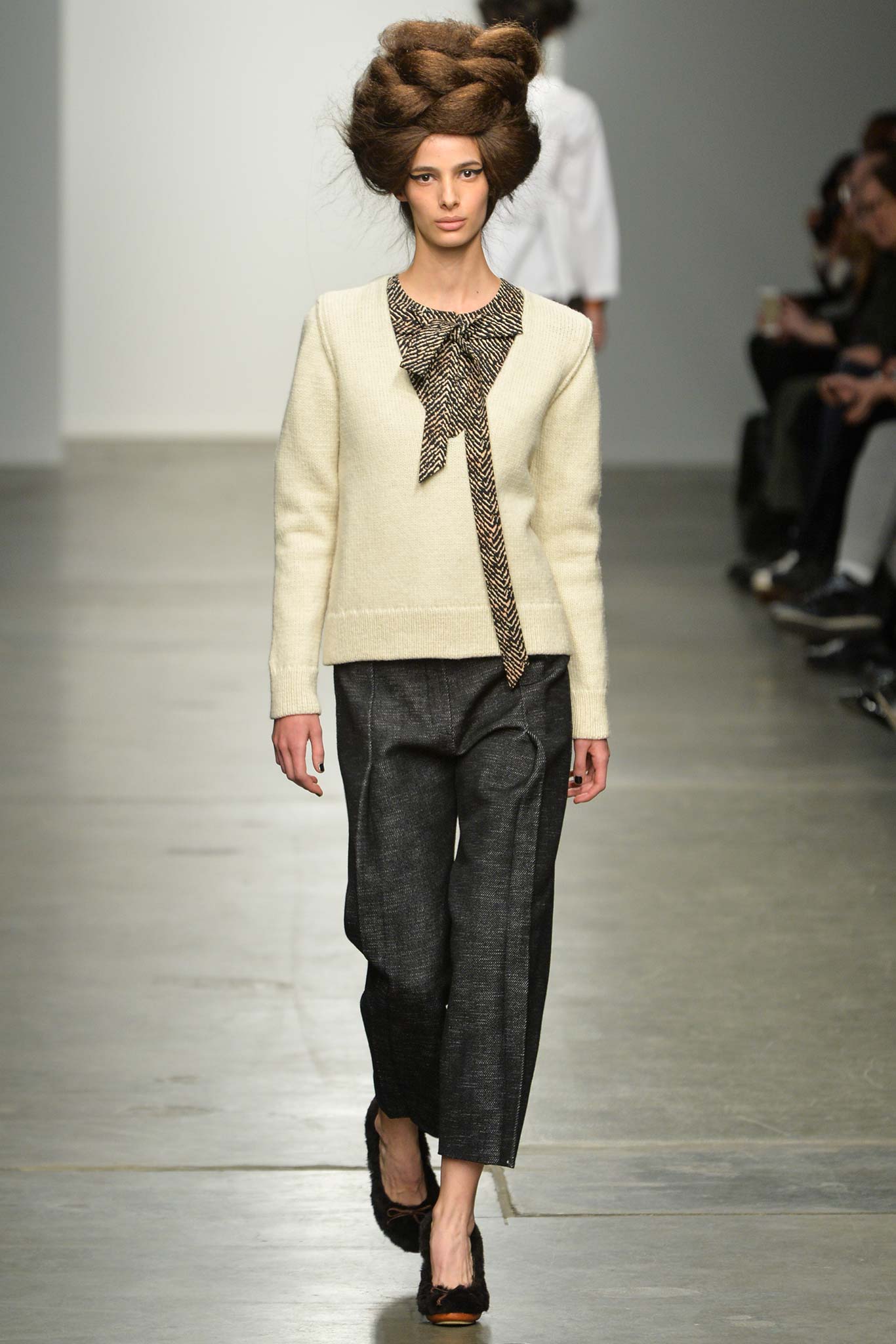 A relaxed cream long-sleeve sweater with a collared design paired with gray pants.