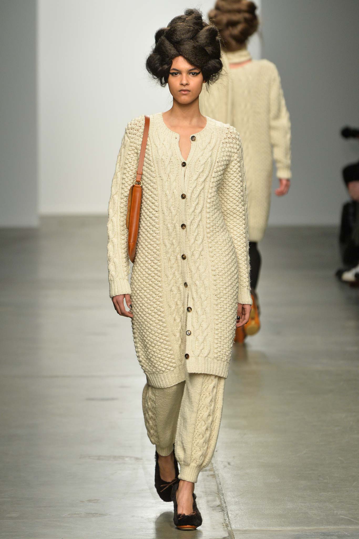 A relaxed cream wool cardigan with long sleeves and knitted texture paired with matching pants.