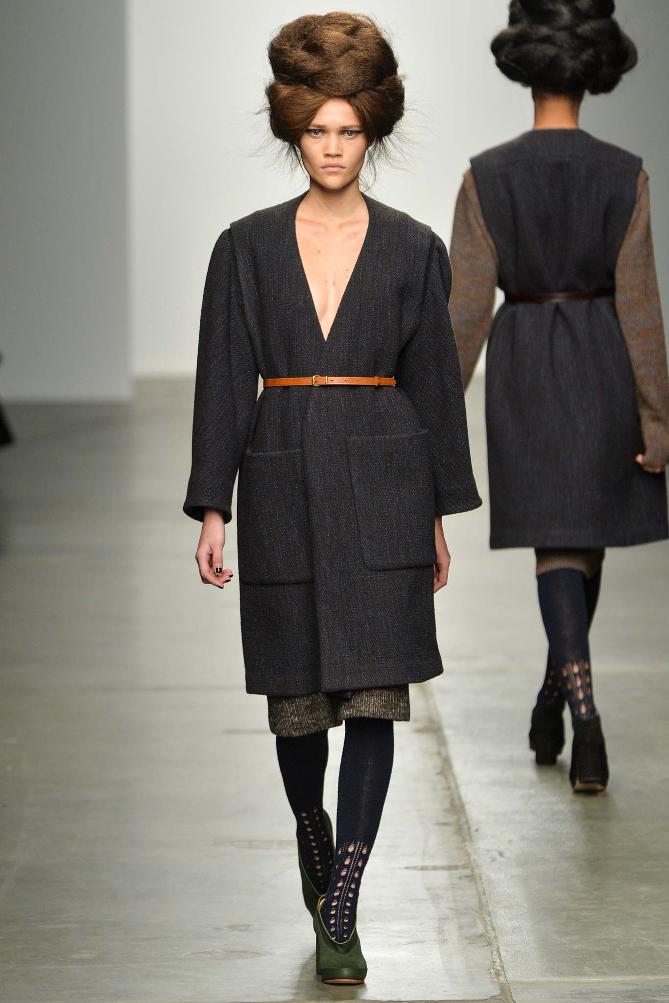 A relaxed black wool coat with a V-neckline and belted detail.