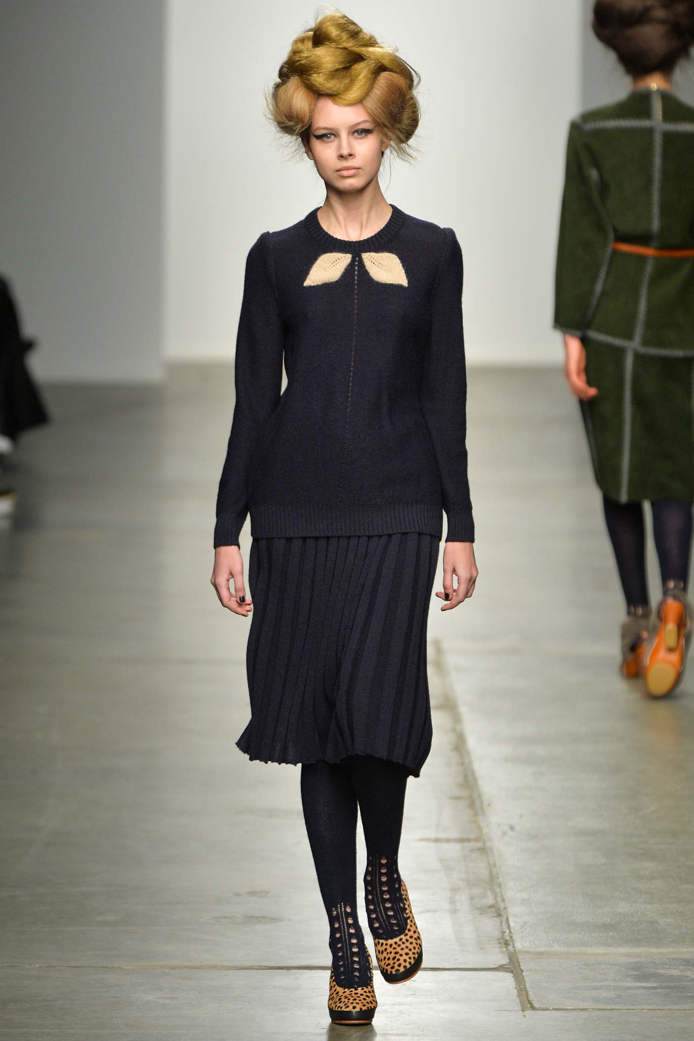A fitted navy dress with long sleeves, a crew neckline, and pleated detailing.