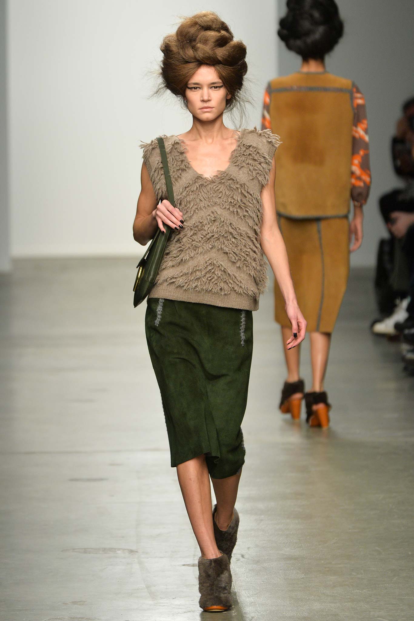 A fitted brown wool sleeveless top with a V-neck and a green suede straight-leg skirt.