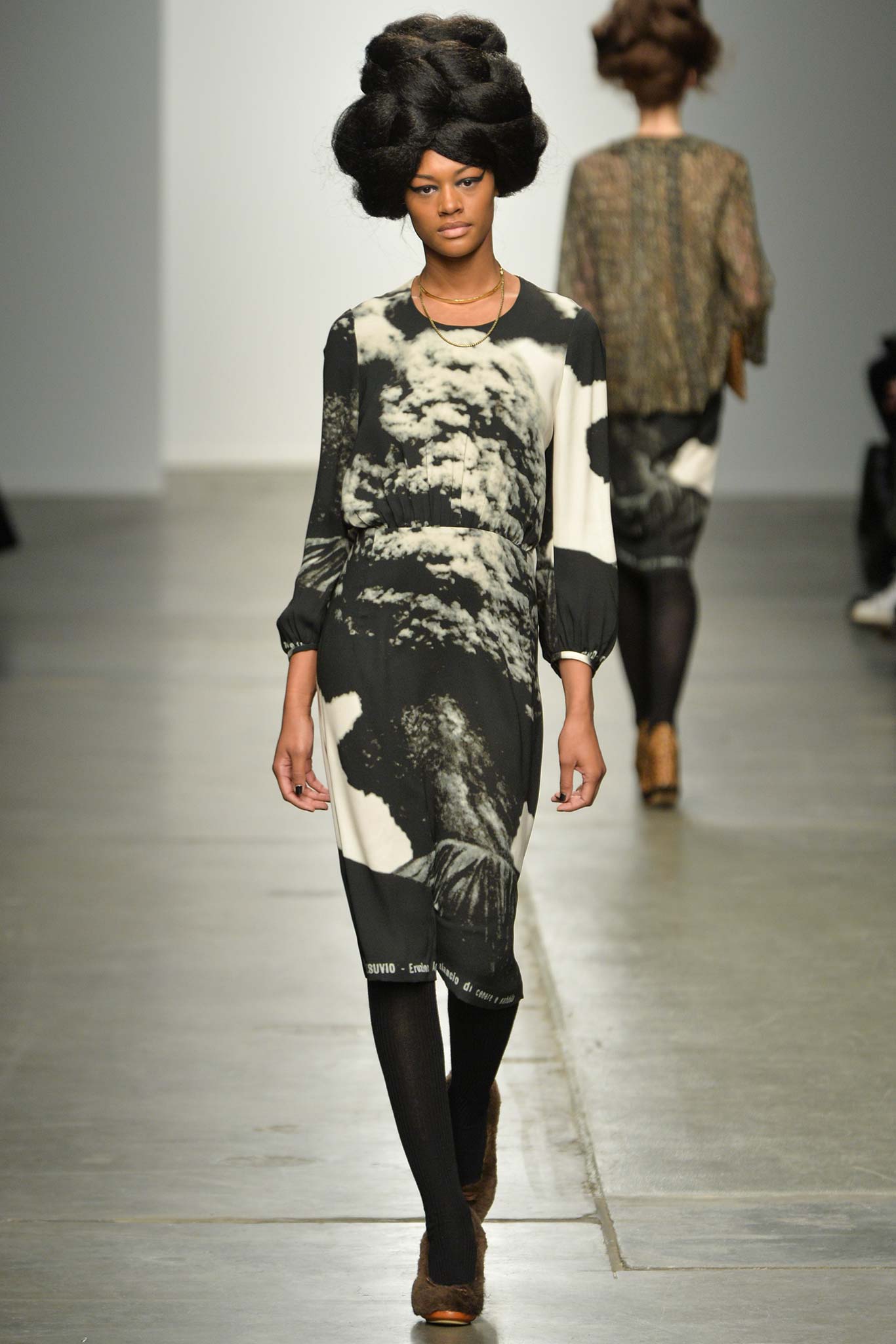 A fitted black and white printed dress with long sleeves and a crew neckline.