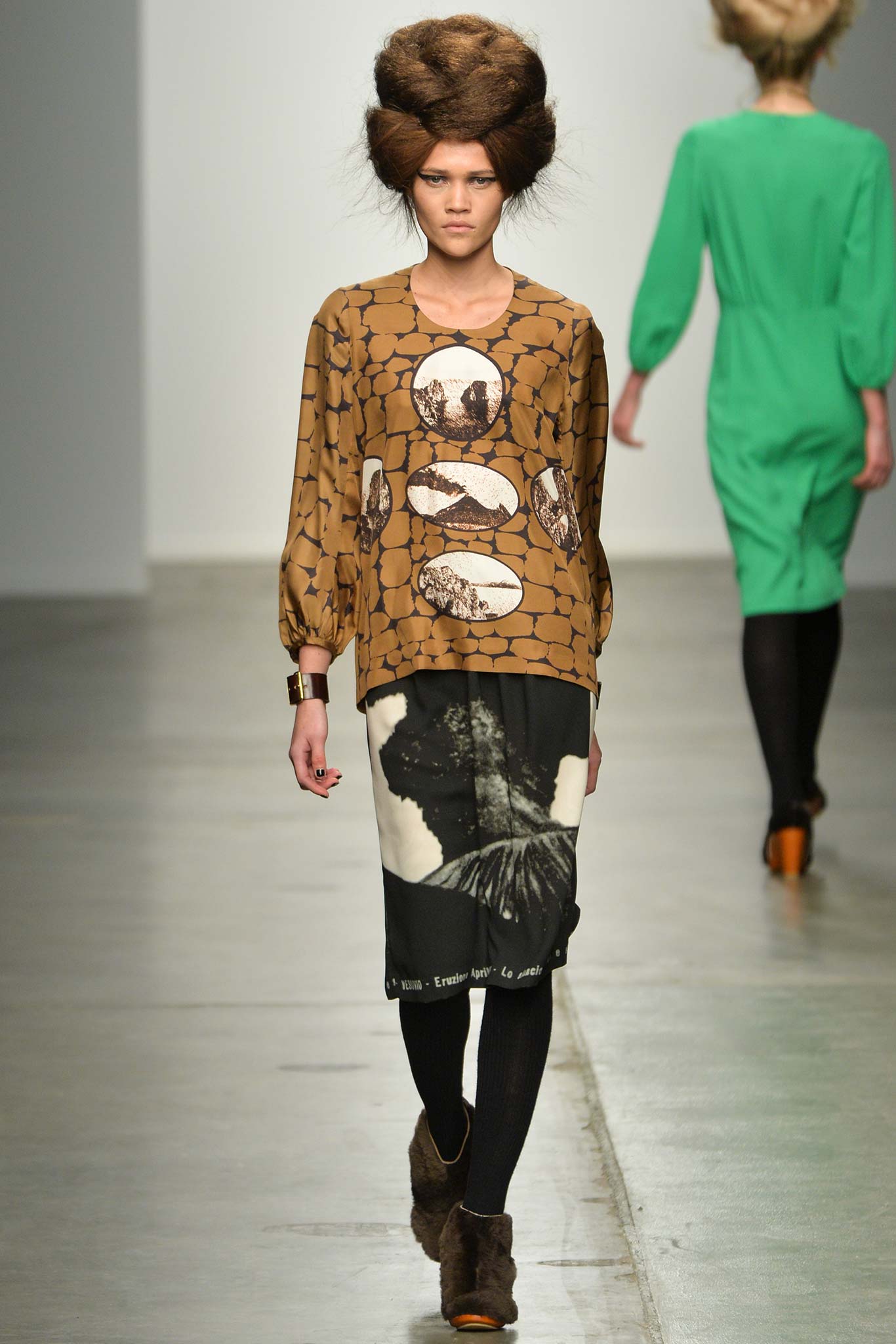 A fitted brown long-sleeve top with a printed design paired with a black skirt.