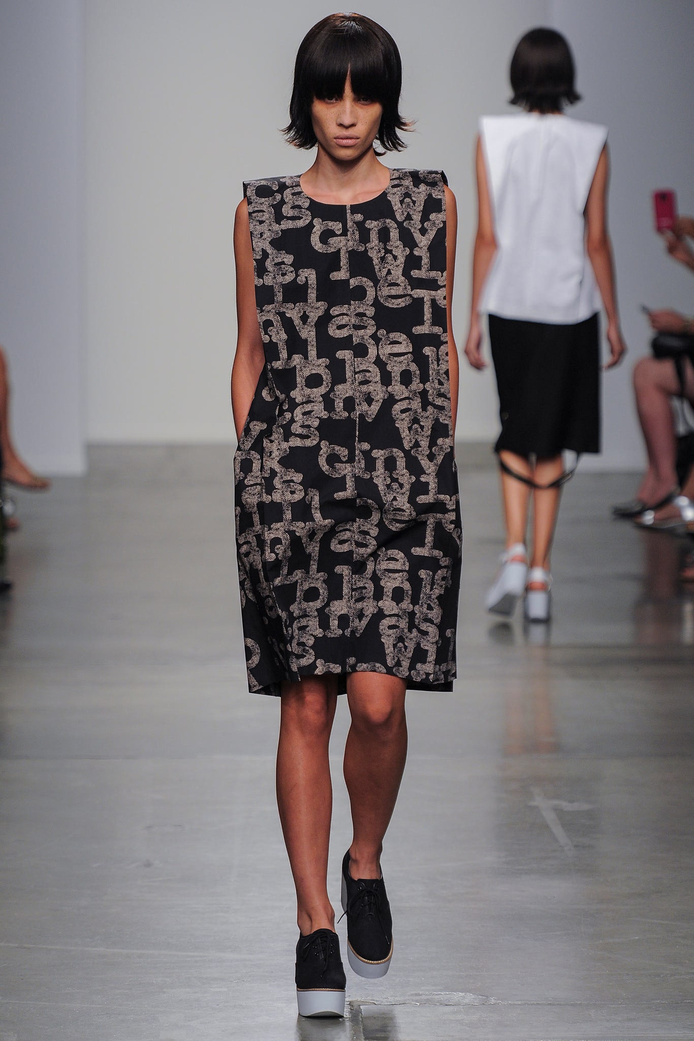 A relaxed black dress with a printed design and sleeveless, collared construction.