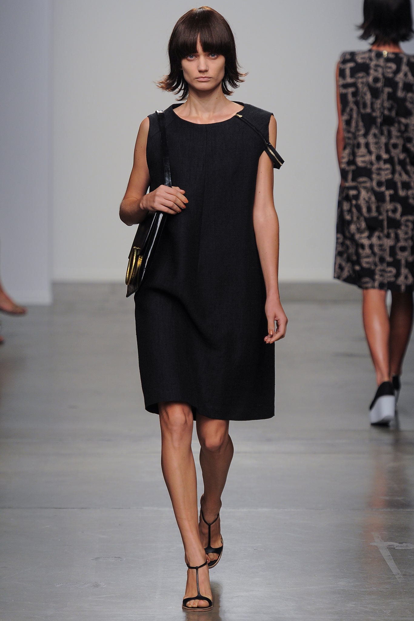 A relaxed black cotton sleeveless dress with a high neckline and straight silhouette.